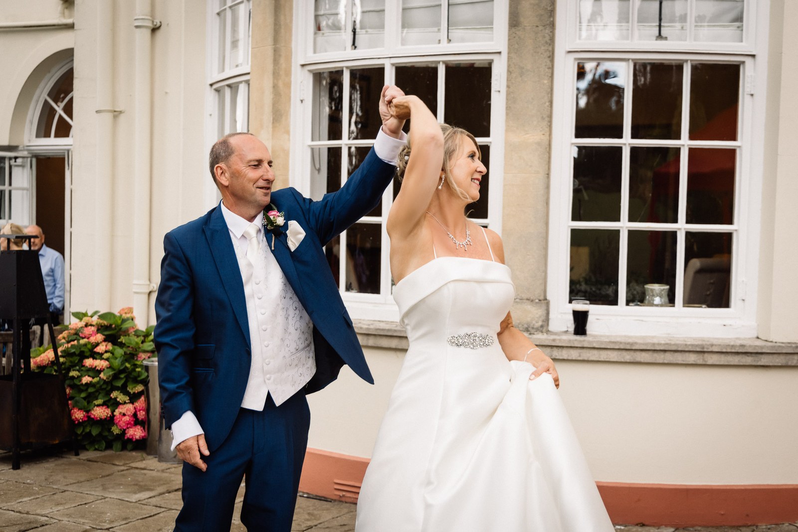 The groom twirling the bride on the terrace outside Glenfall House