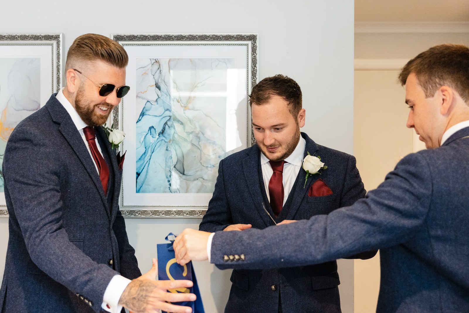 Groomsmen in navy tweed handing over a gift bag before the ceremony