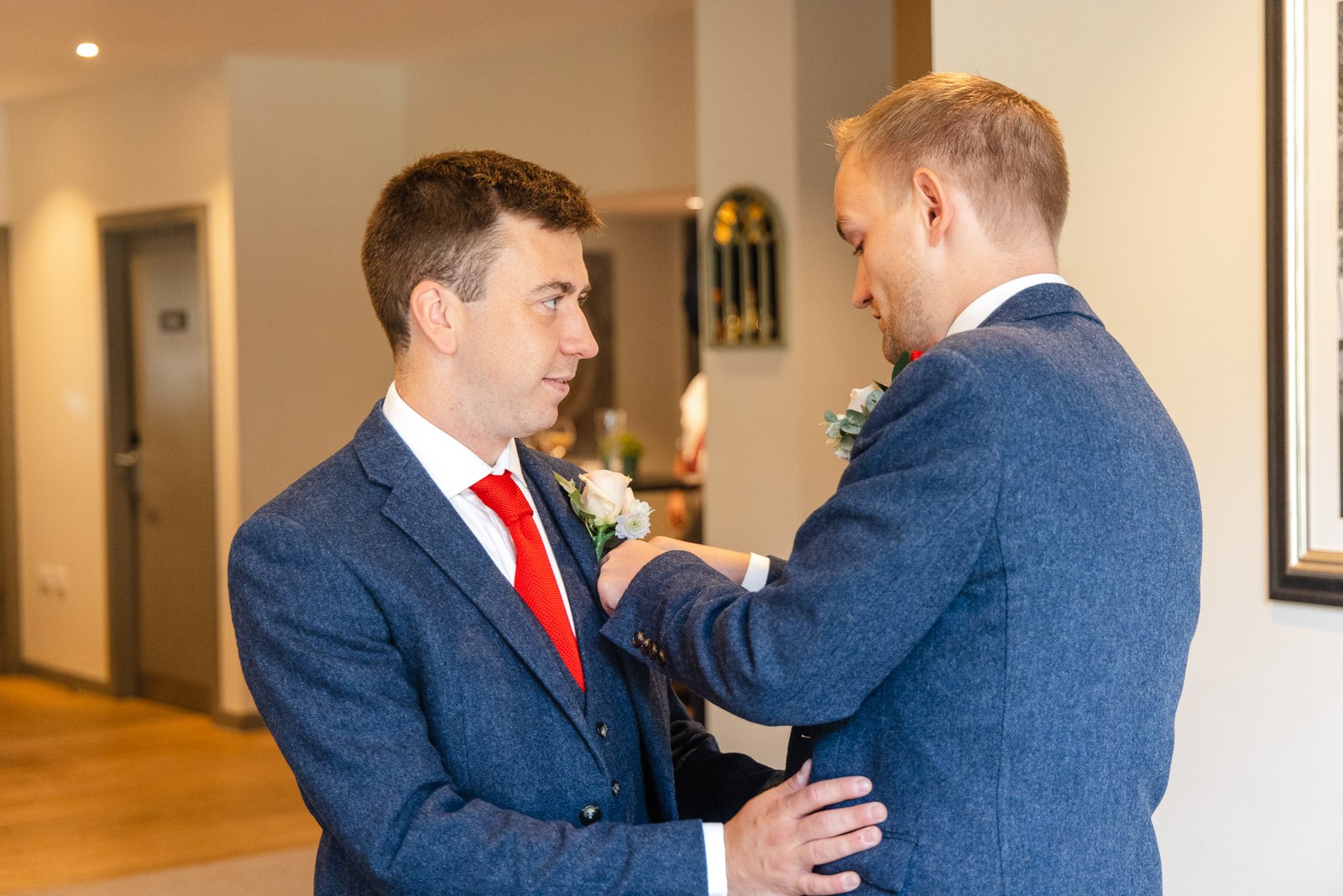 One groom pinning the other's buttonhole before the ceremony