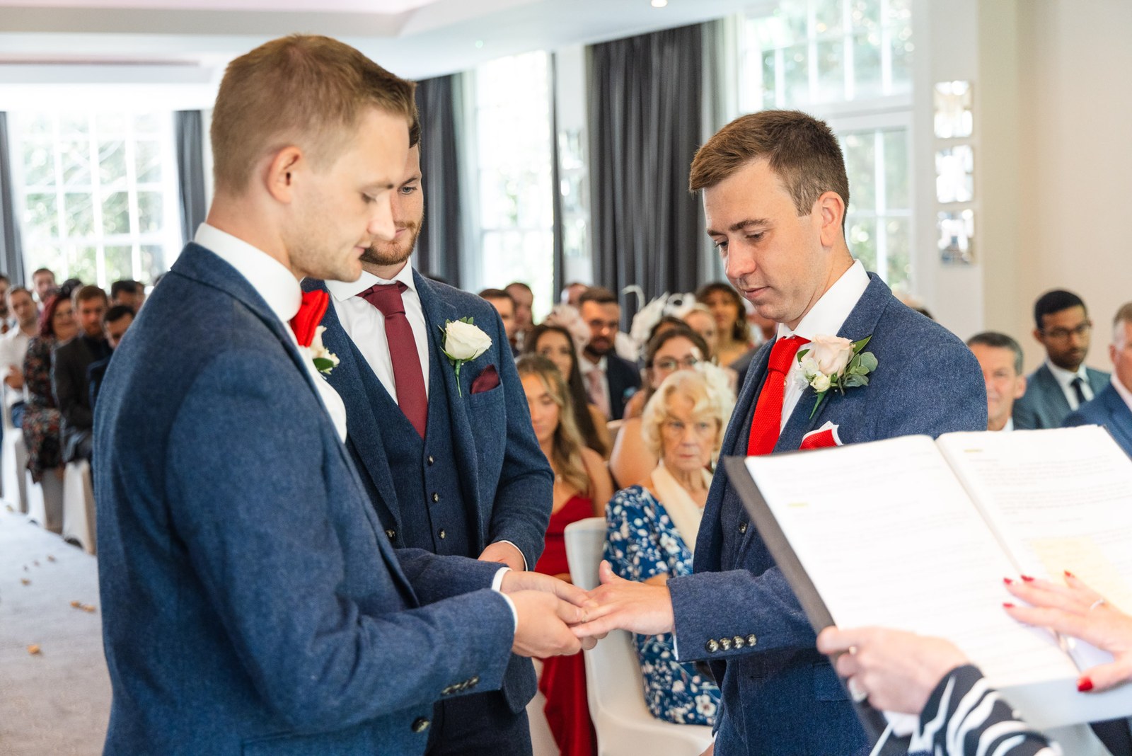 The grooms exchanging rings during the ceremony as the registrar looks on