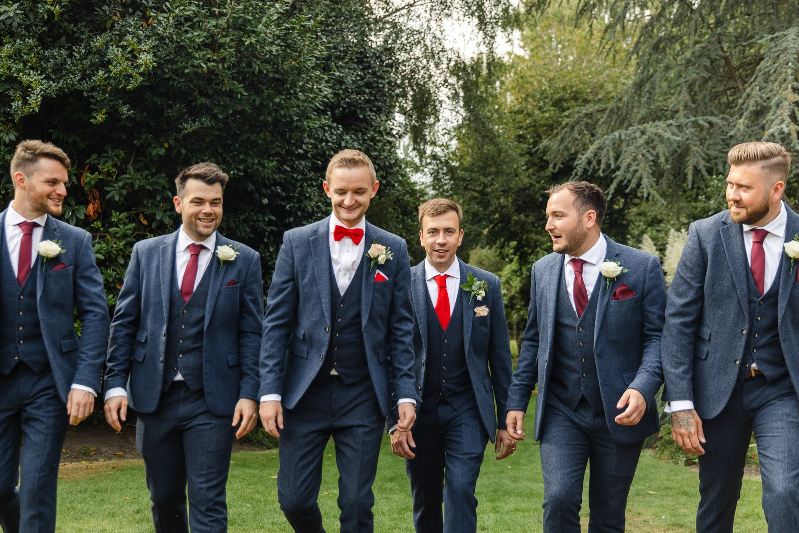 The grooms and groomsmen walking and laughing through the grounds of Gorse Hill Hotel