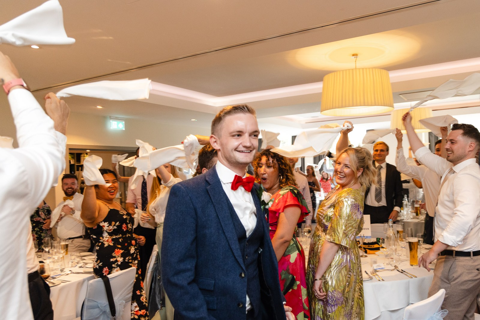 A groom entering the reception through a guard of waving napkins
