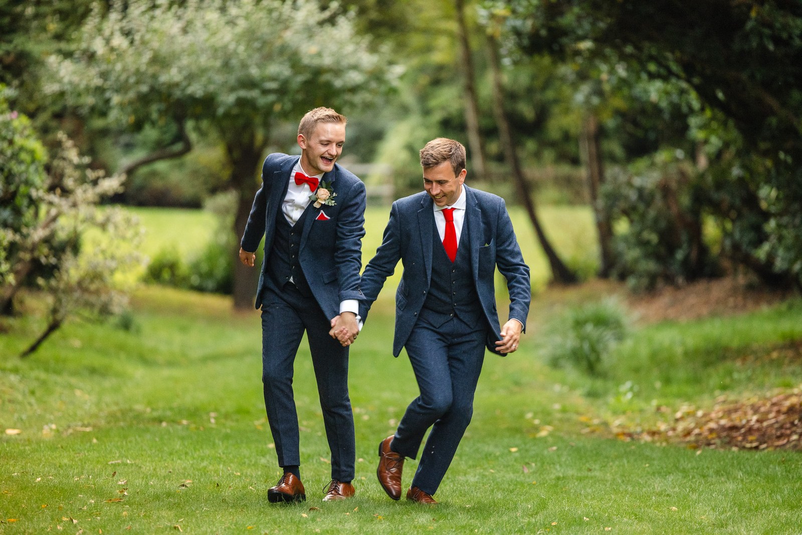 The two grooms walking hand in hand across the lawns of Gorse Hill Hotel