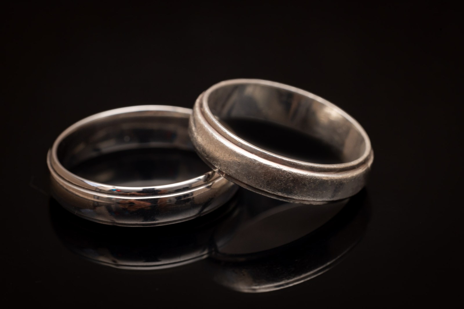 Close-up of the pair of wedding rings on a dark reflective surface