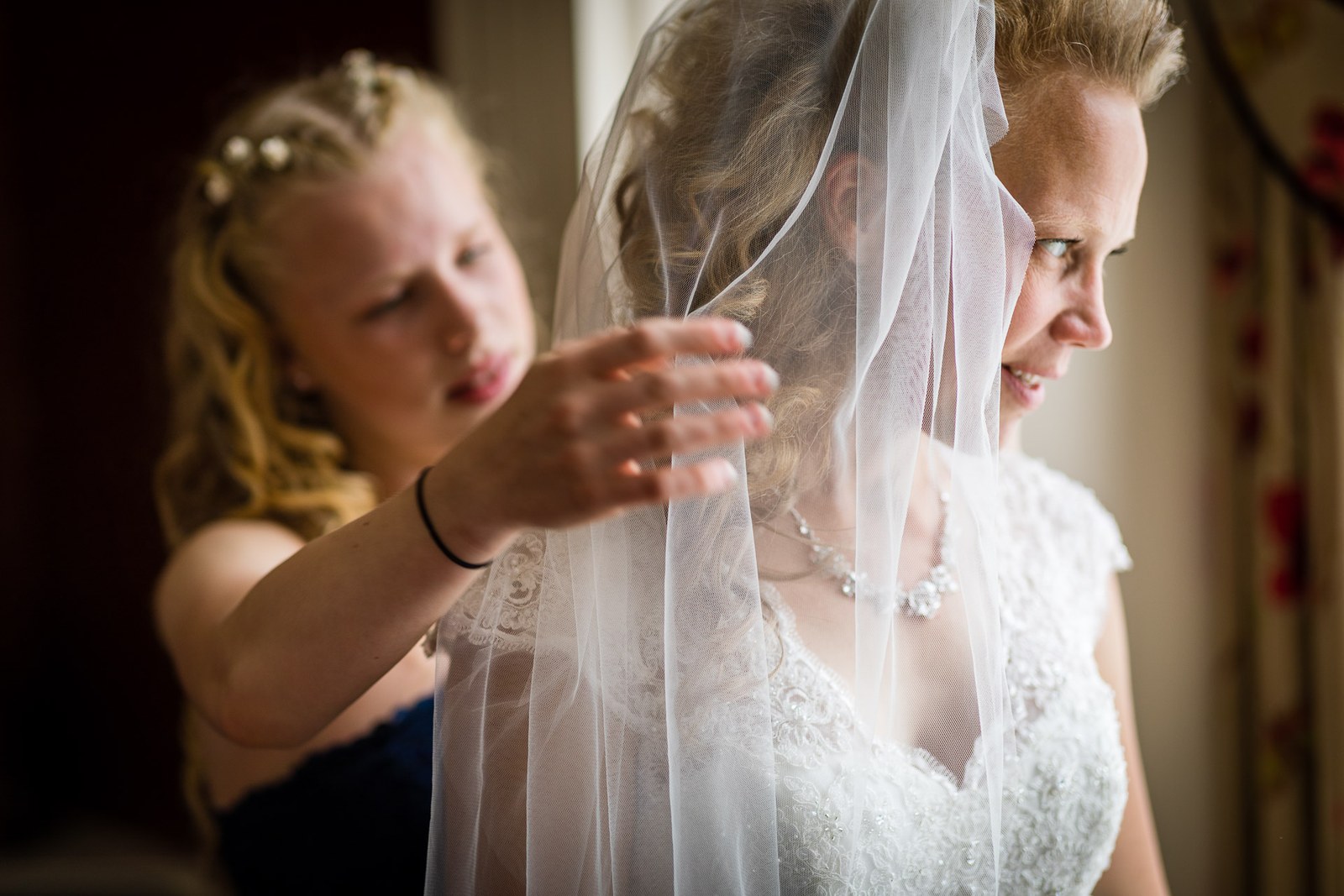 A bridesmaid arranging the veil over the bride's face during the final touches
