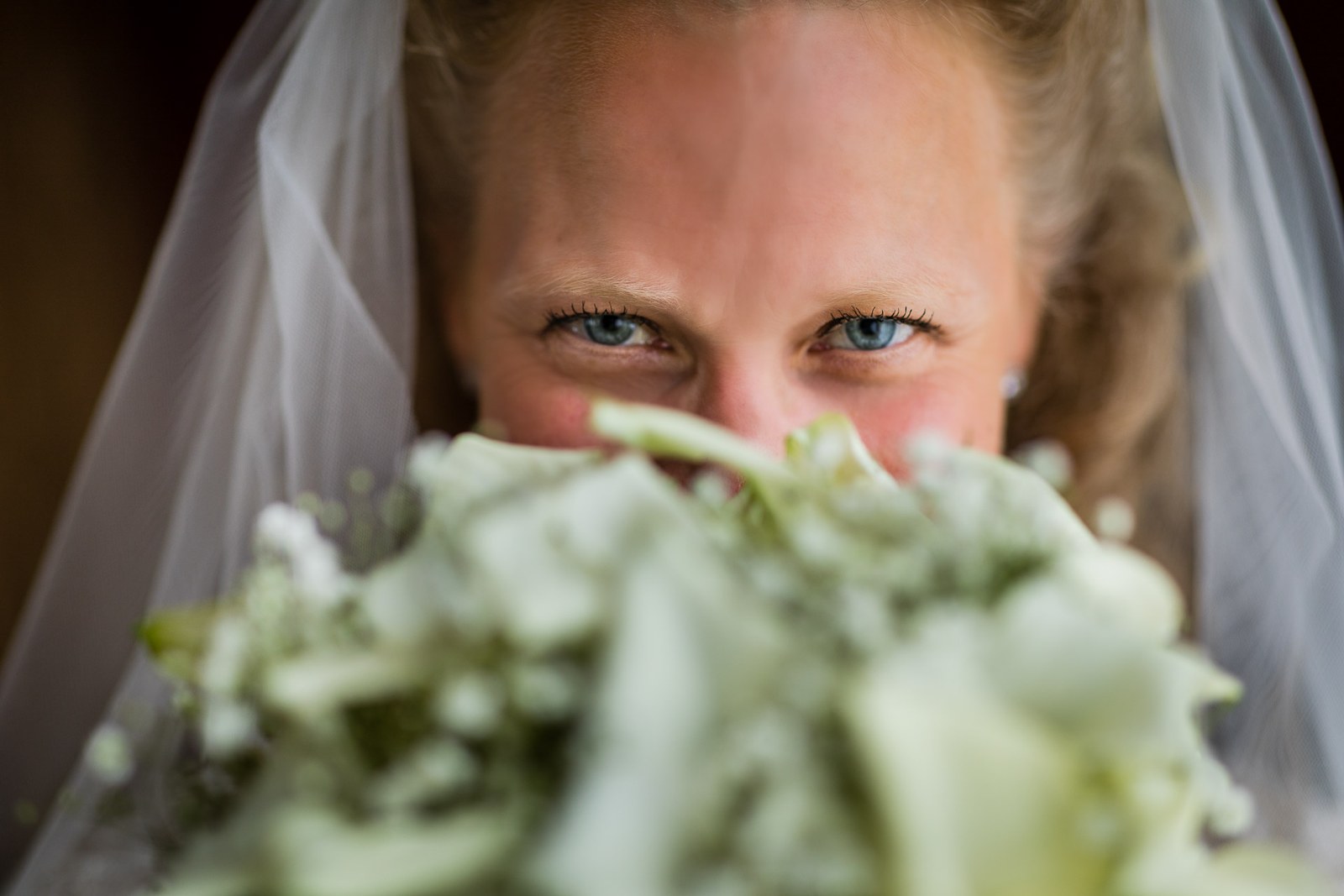 The bride's eyes above her calla lily bouquet