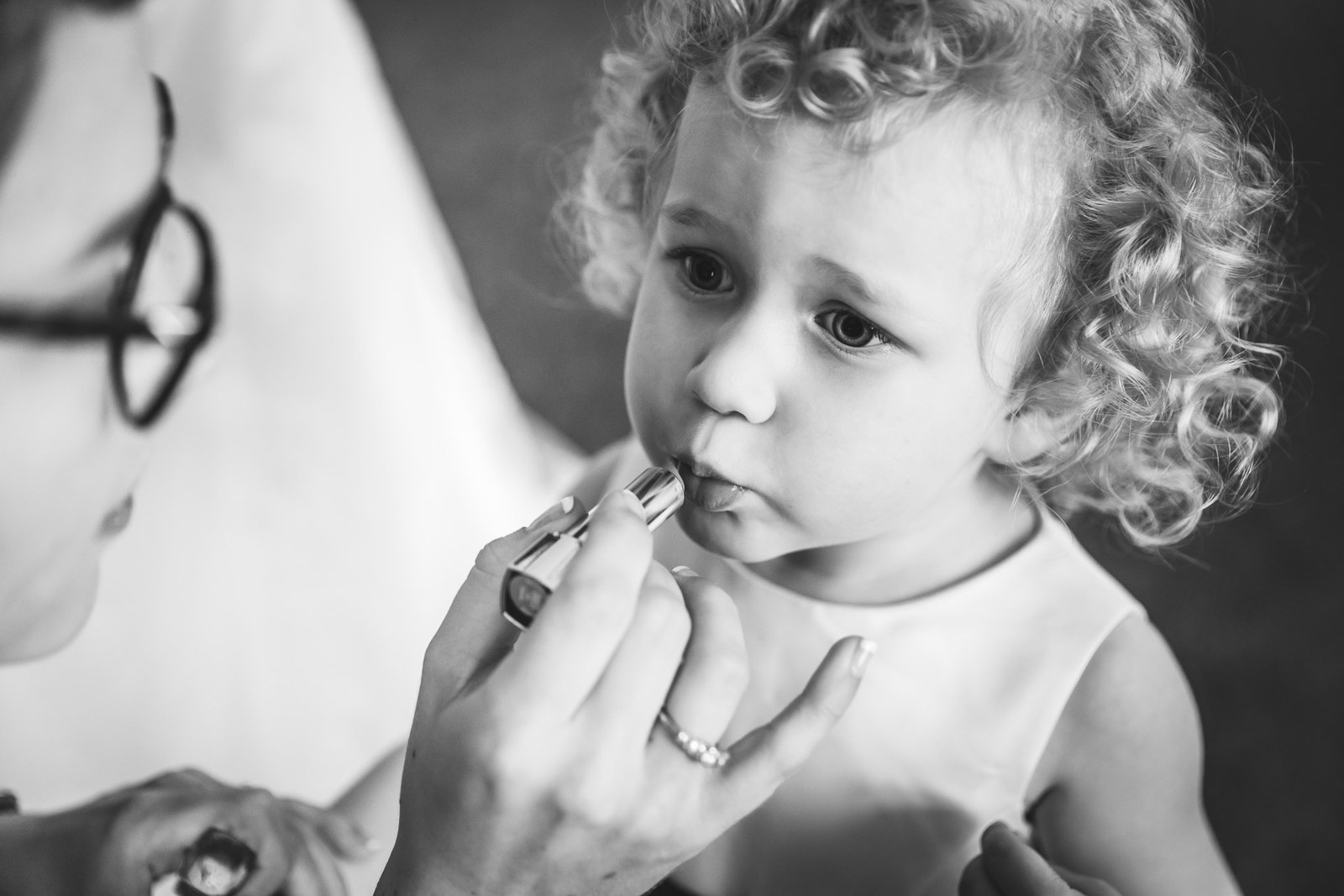 Black-and-white of a flower girl having lipstick carefully applied