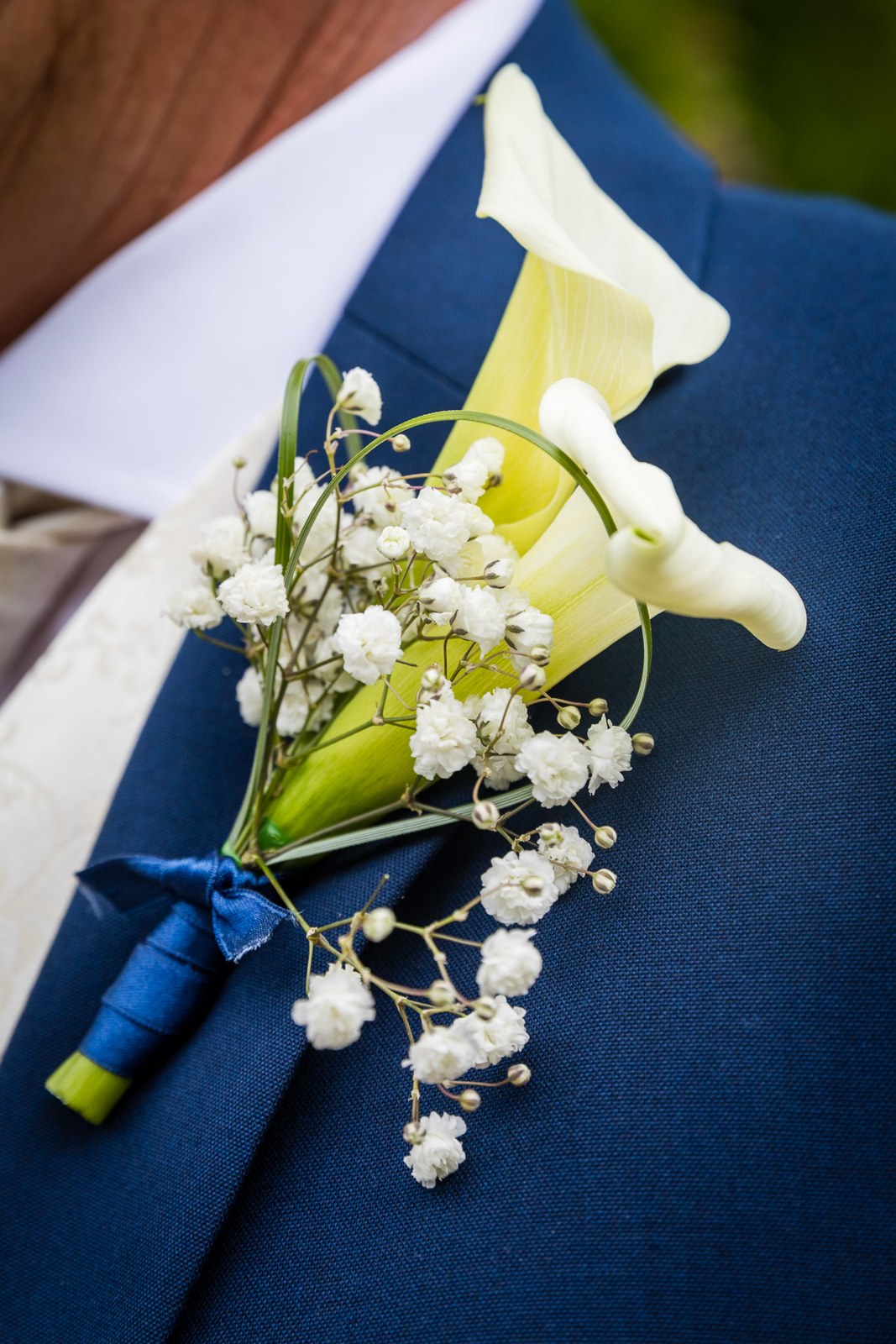 Close-up of the groom's buttonhole, a calla lily and gypsophila with blue ribbon