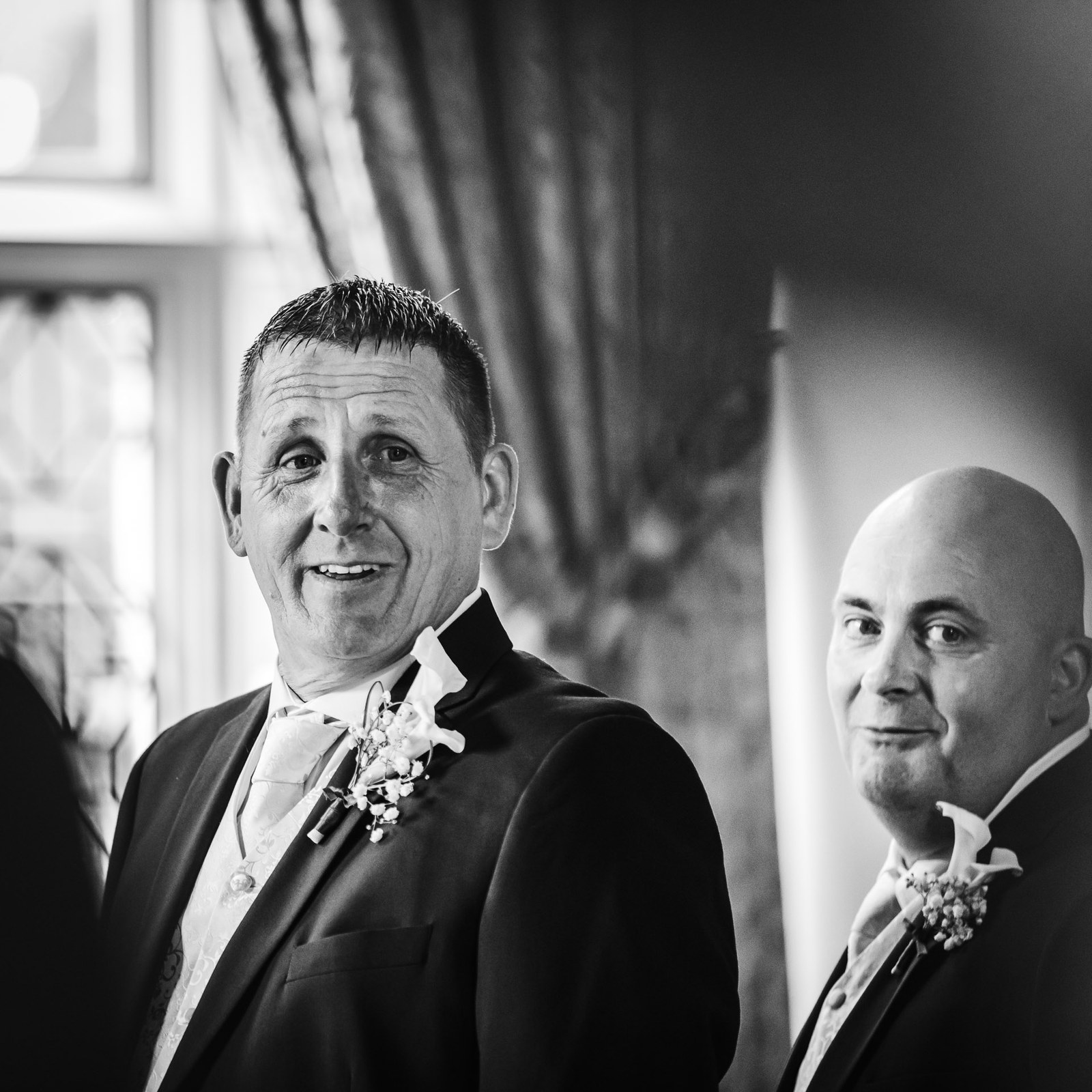 Black-and-white split portrait of the groom and best man smiling