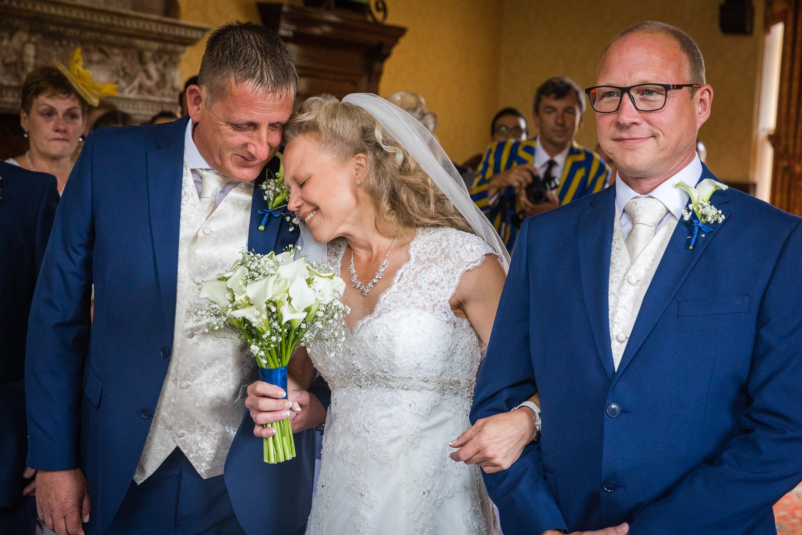 The groom resting his head against the bride's as her father gives her away