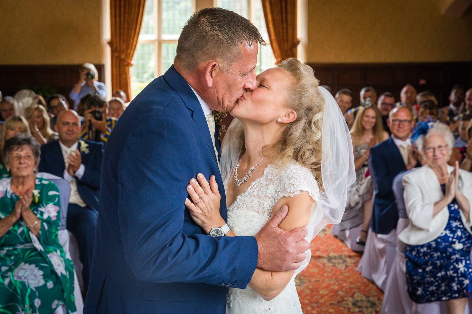 The couple's first kiss in the panelled ceremony hall at Grim's Dyke Hotel as guests applaud