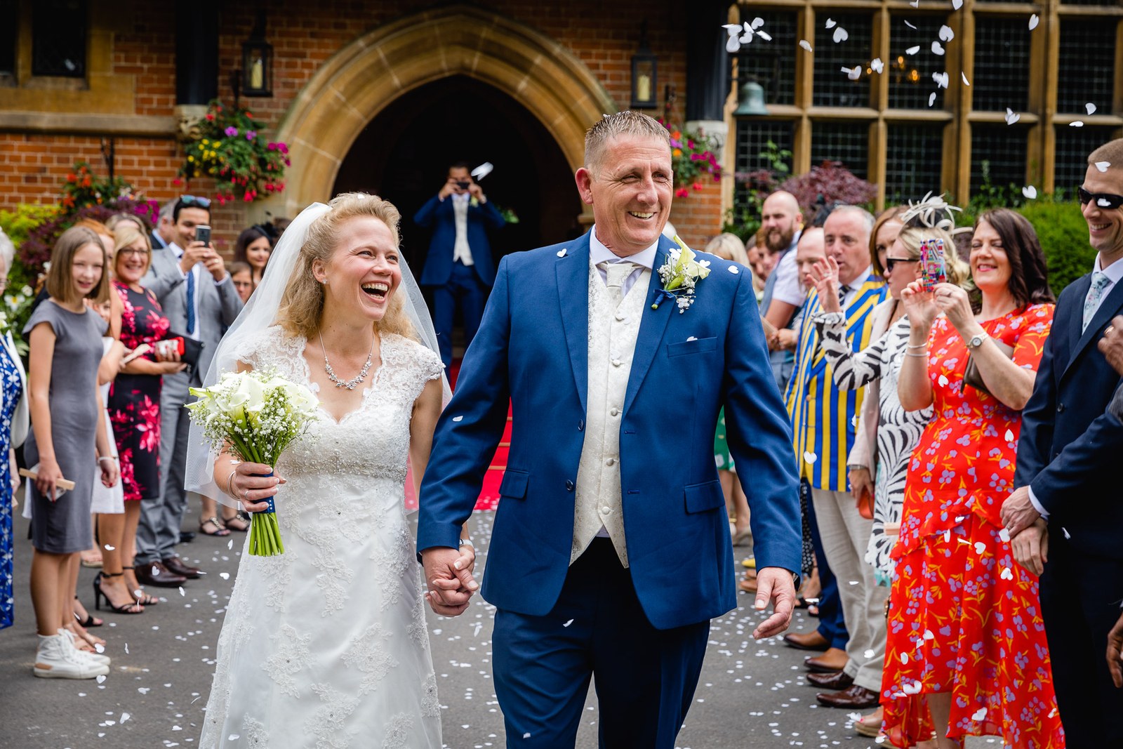 Newlyweds walking through confetti at the arched brick entrance of Grim's Dyke Hotel