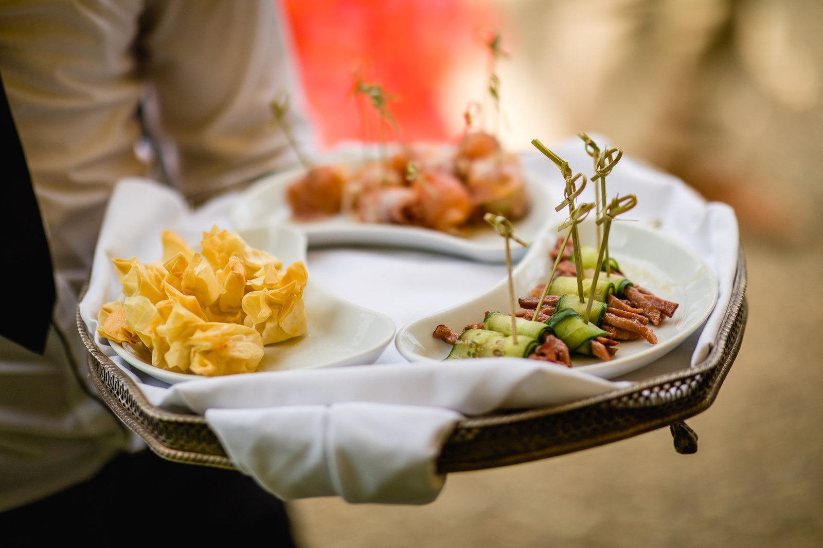 A waiter carrying a tray of canapes through the reception