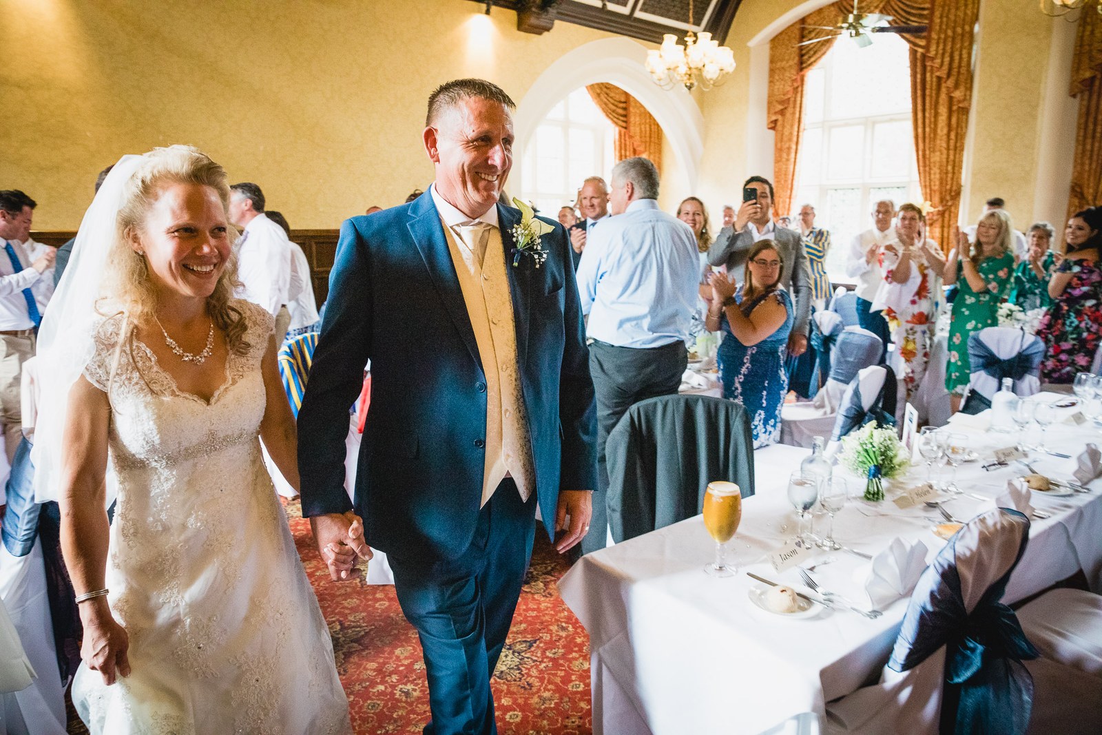 Newlyweds entering the reception hall at Grim's Dyke Hotel to applauding guests