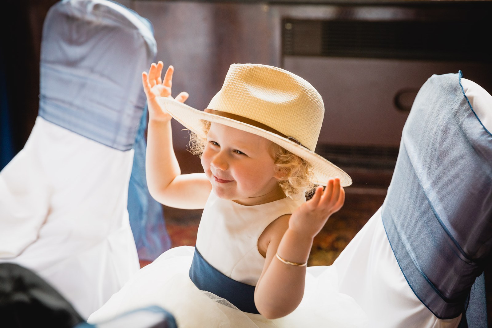 A flower girl in a straw hat waving from her chair