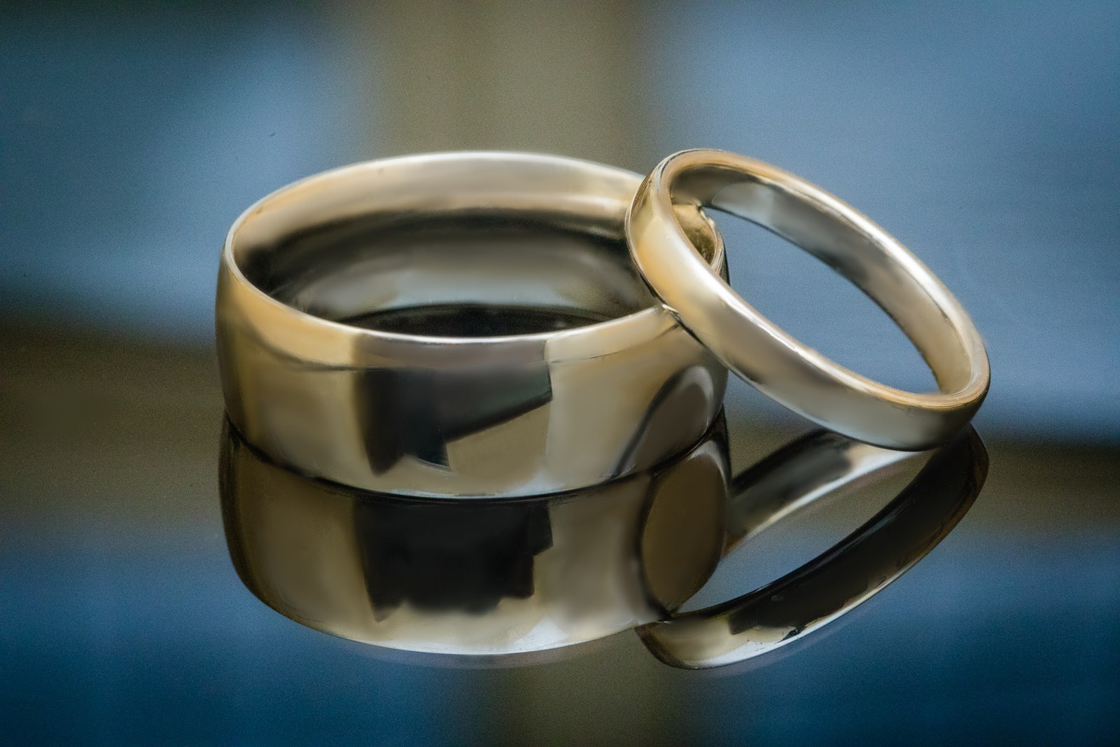 Close-up of the two wedding rings on a reflective blue surface
