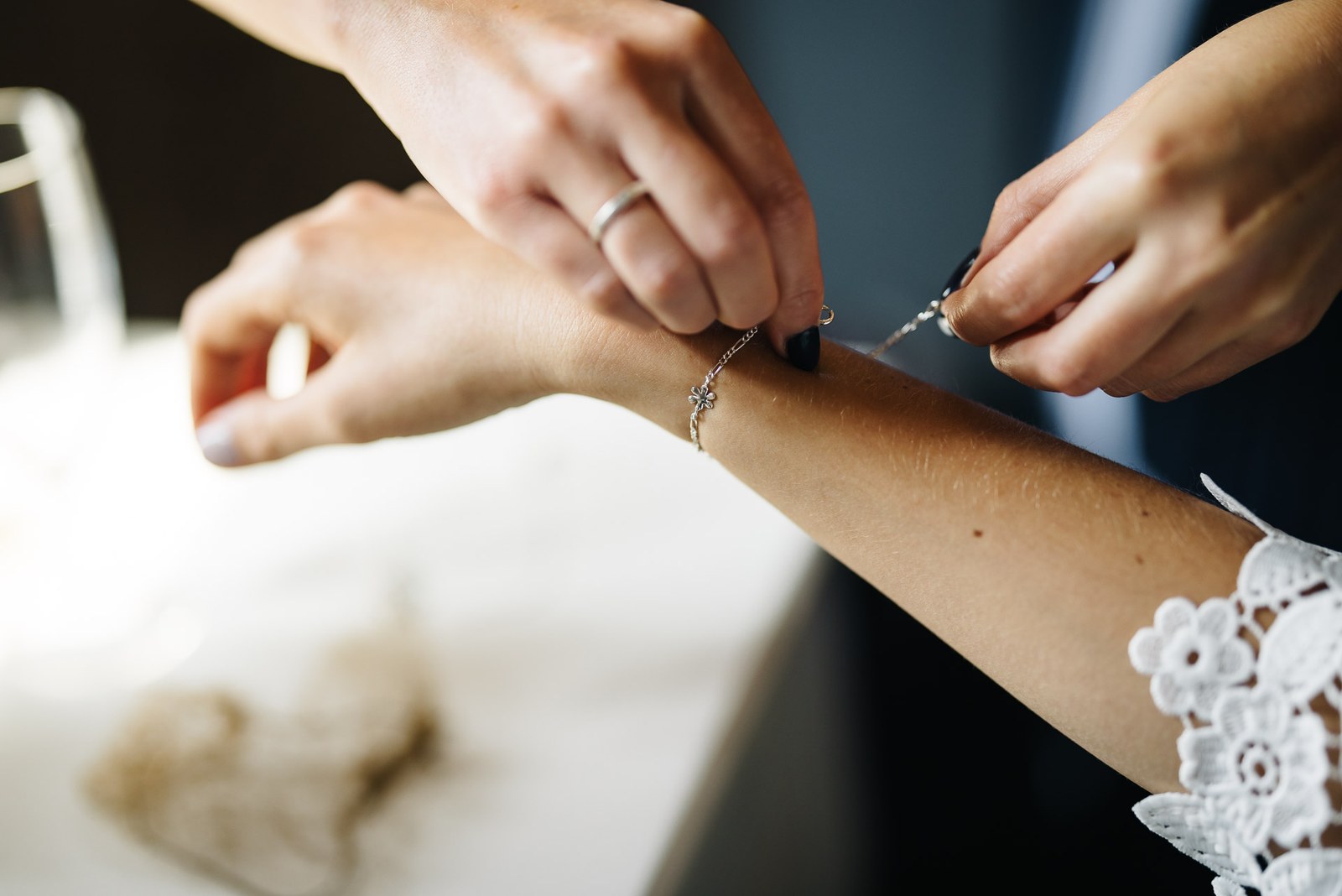 Close-up of a bridesmaid fastening a delicate bracelet on the bride's wrist