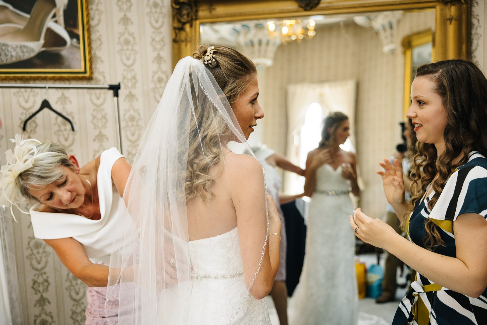 The mother of the bride fixing the veil as a guest looks on