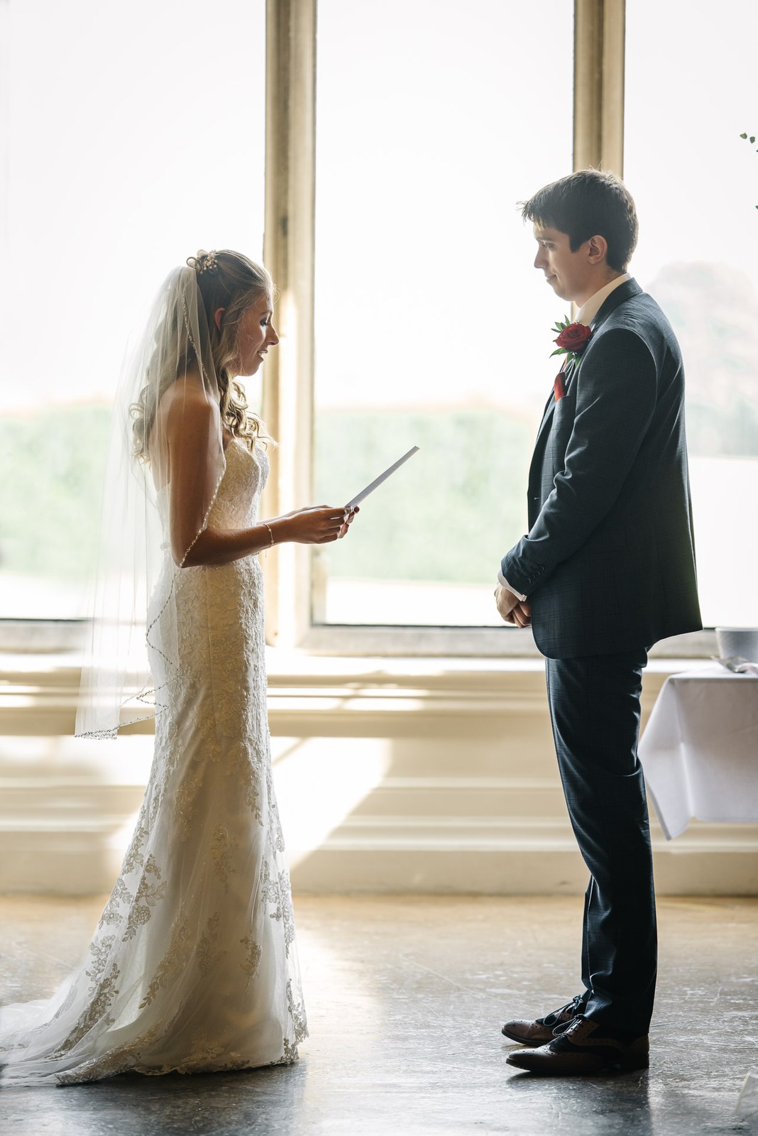Bride reading her vows to the groom in the window light