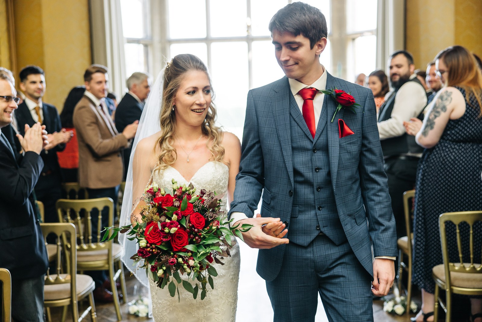 Newlyweds walking back down the aisle as guests applaud