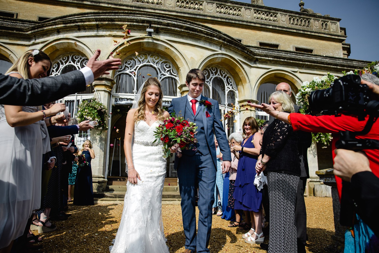 Confetti showering the newlyweds outside the honey-stone frontage of Grittleton House