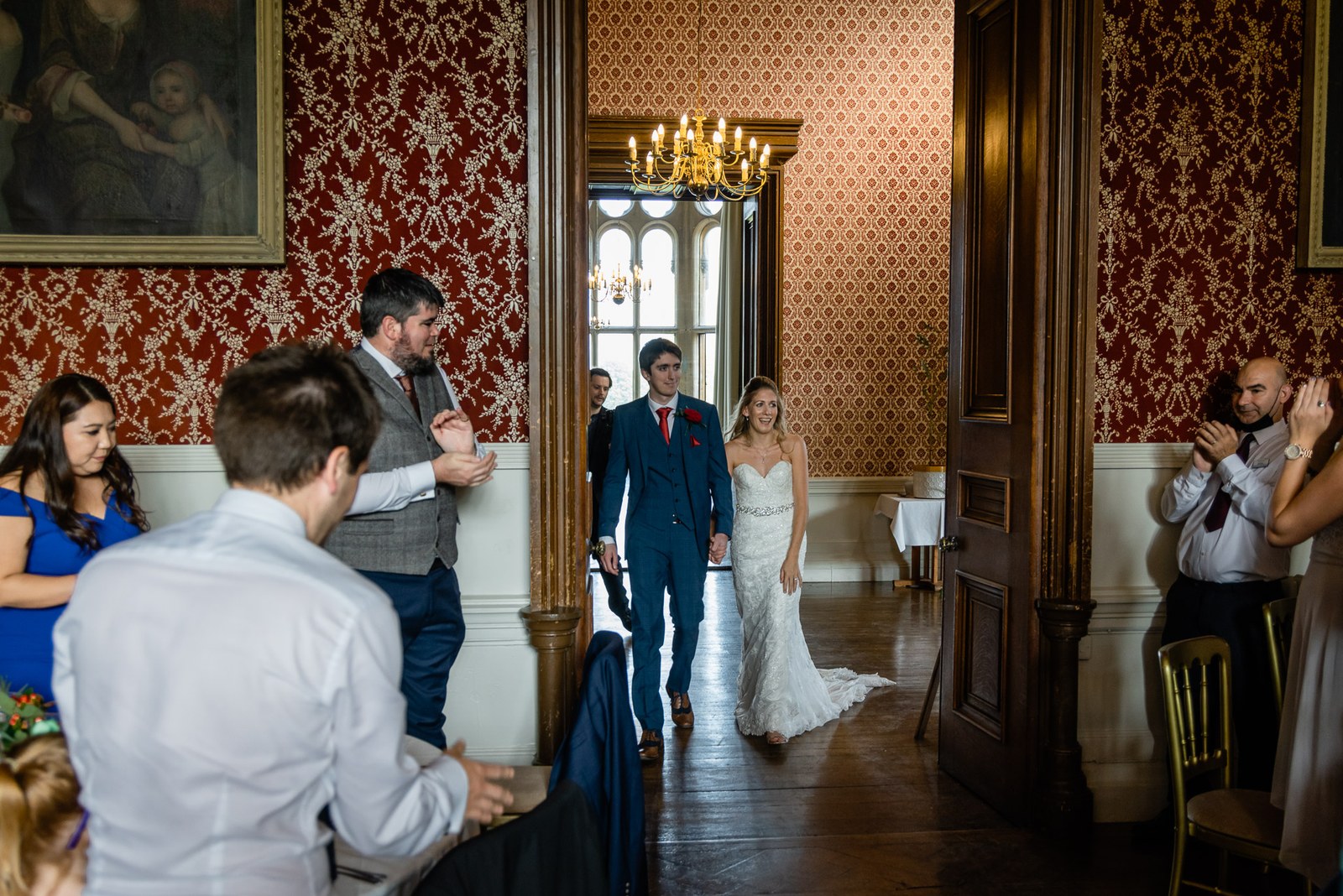 The couple entering the red damask reception room as guests applaud