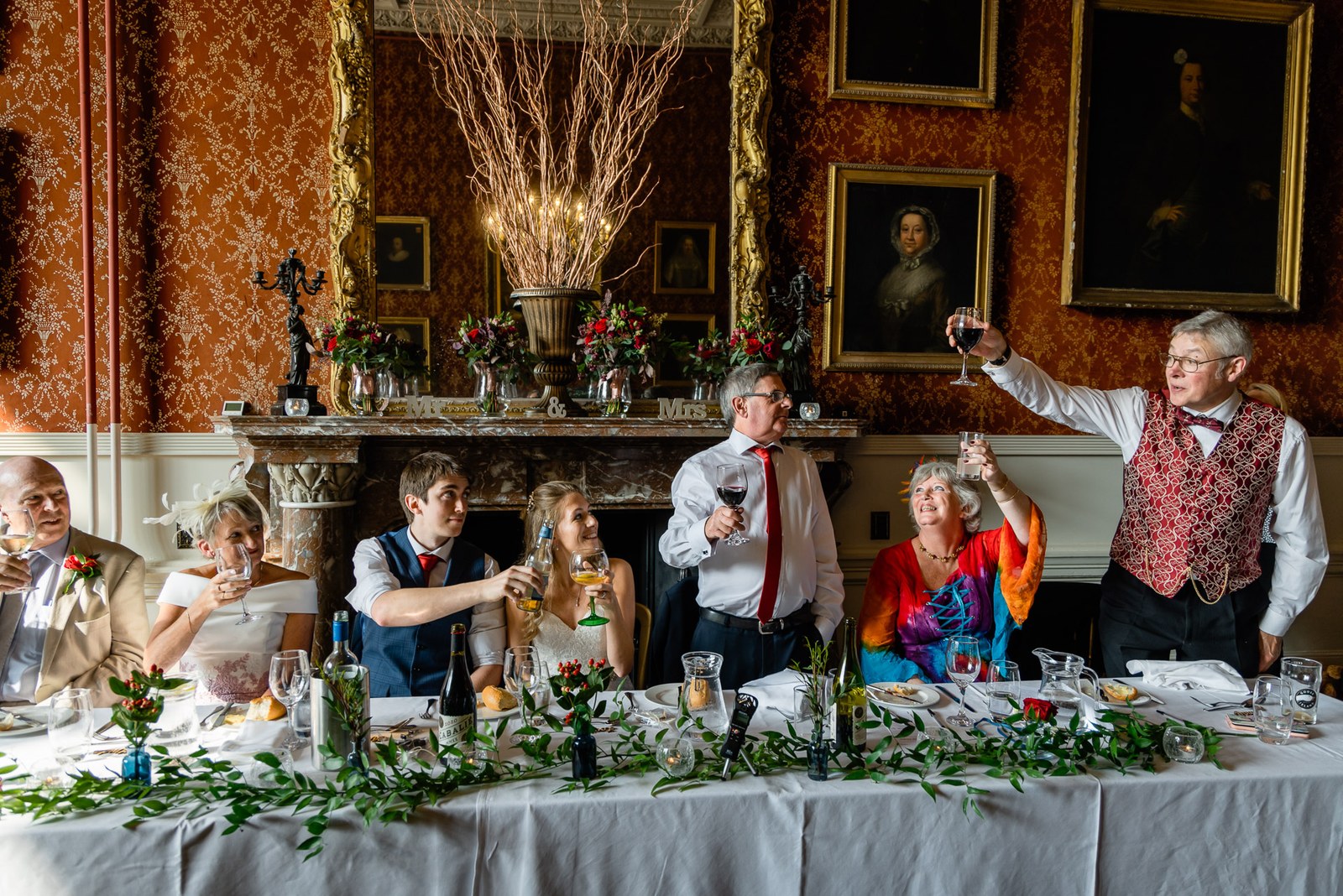 A toast raised at the top table in the portrait-hung red dining room at Grittleton House