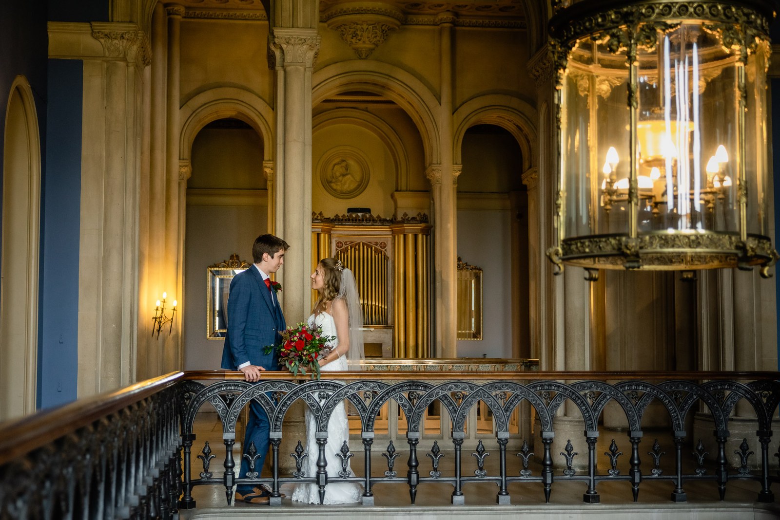 The couple embracing on the staircase landing beneath a grand glass lantern