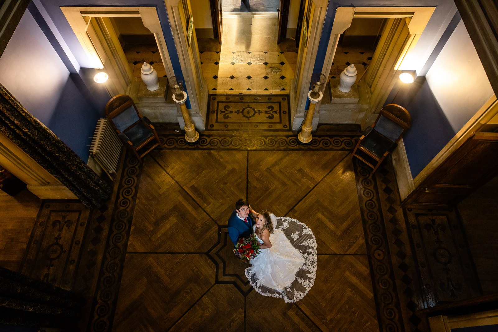 Overhead view of the couple on the parquet floor, the bride's gown fanned around her
