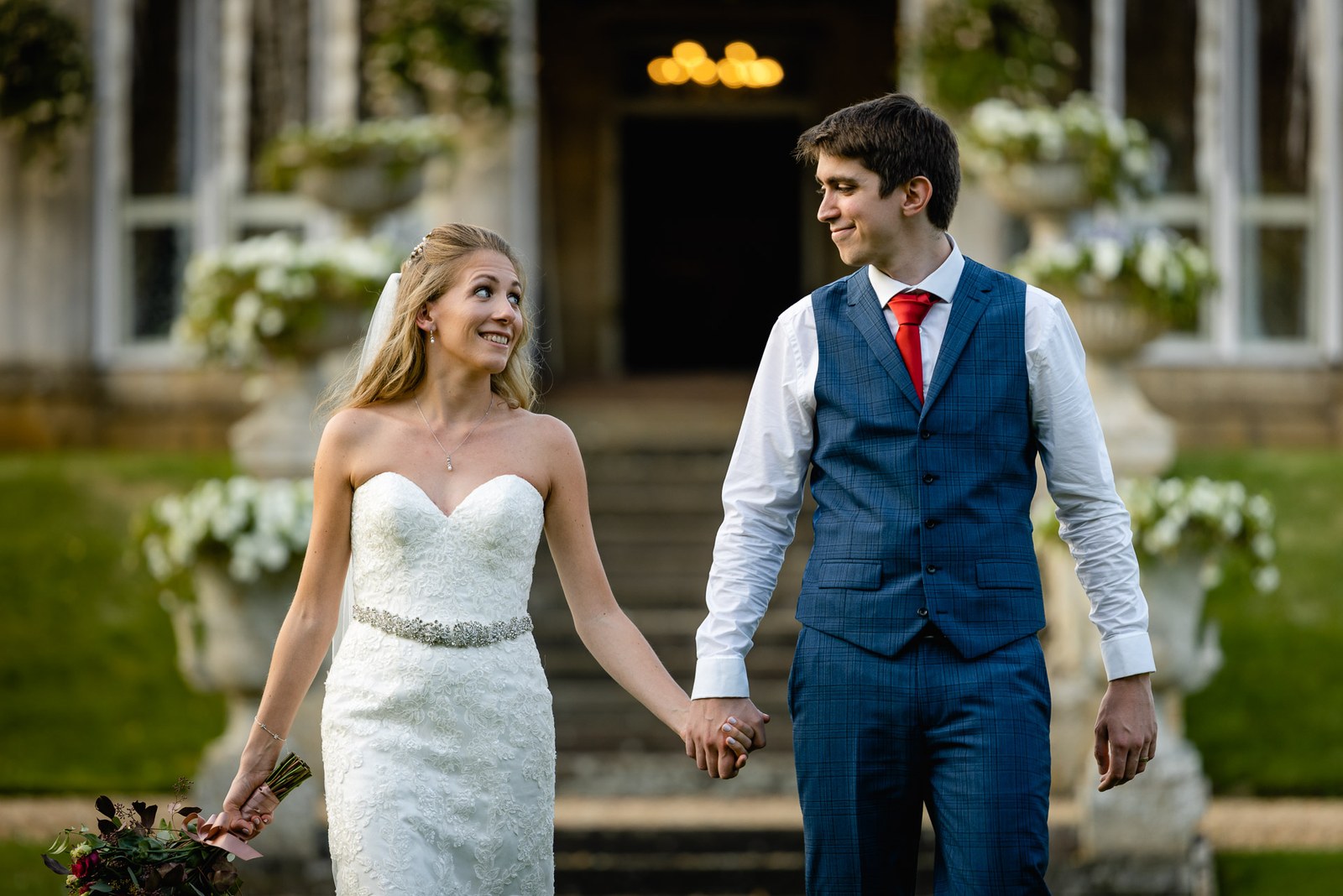 Bride and groom holding hands on the steps outside the house at dusk