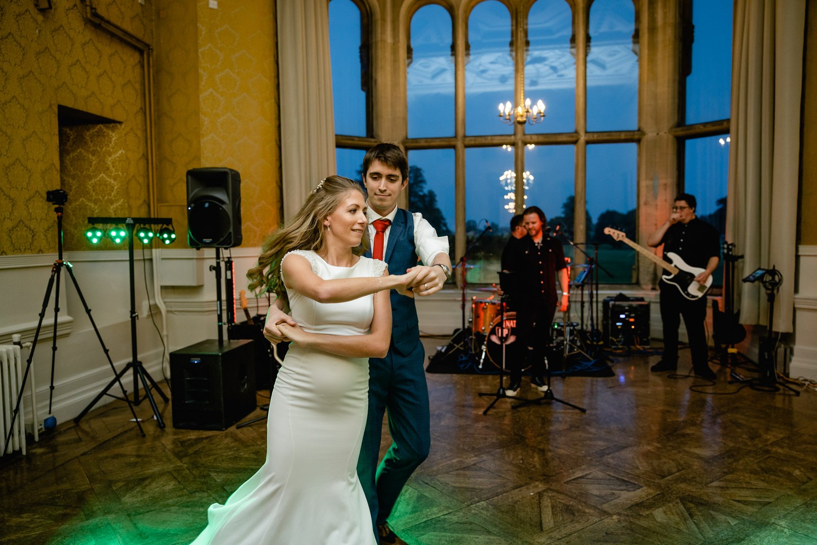The newlyweds' first dance before the live band in the window-lit hall