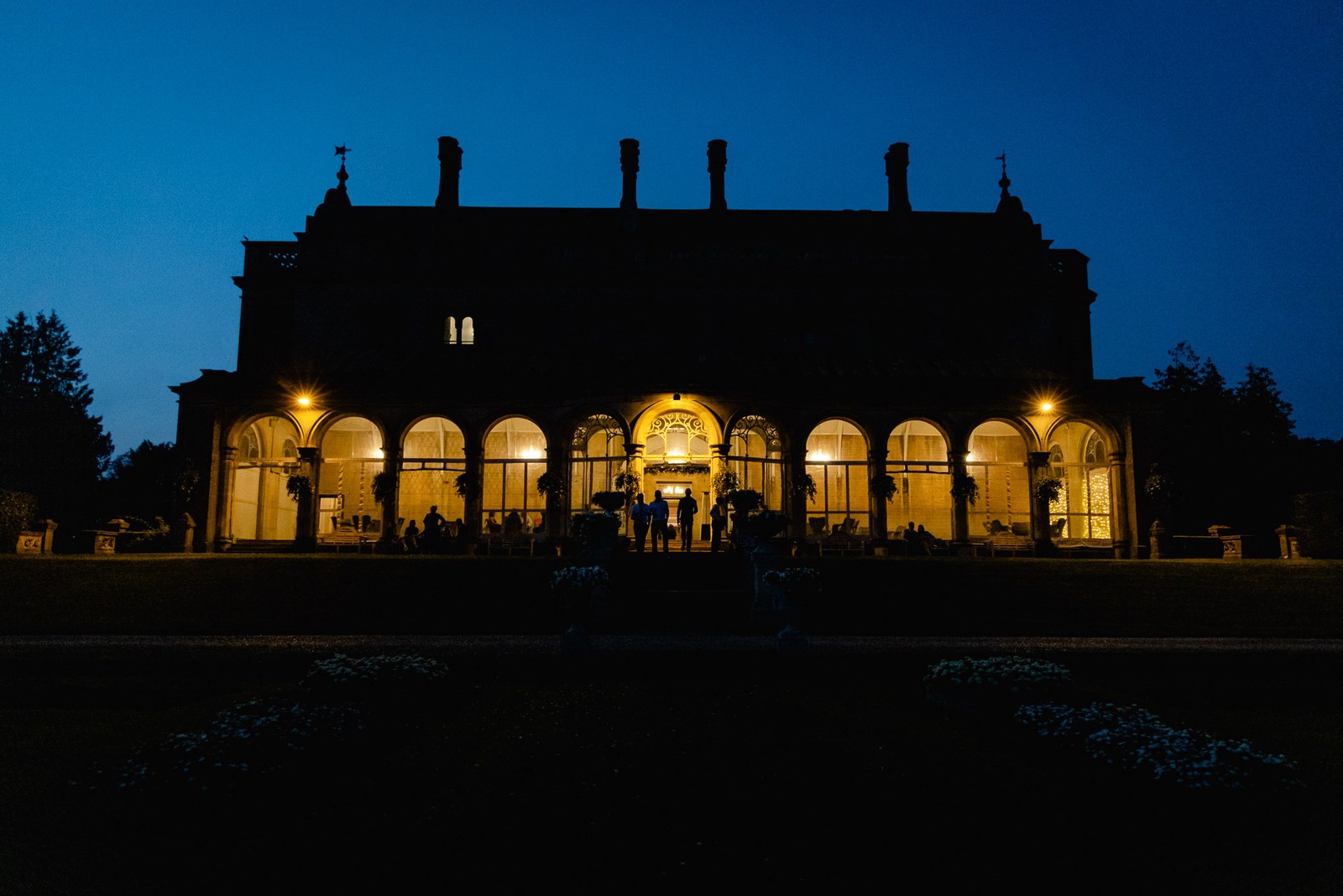 Grittleton House at blue hour, its arched orangery windows glowing warmly