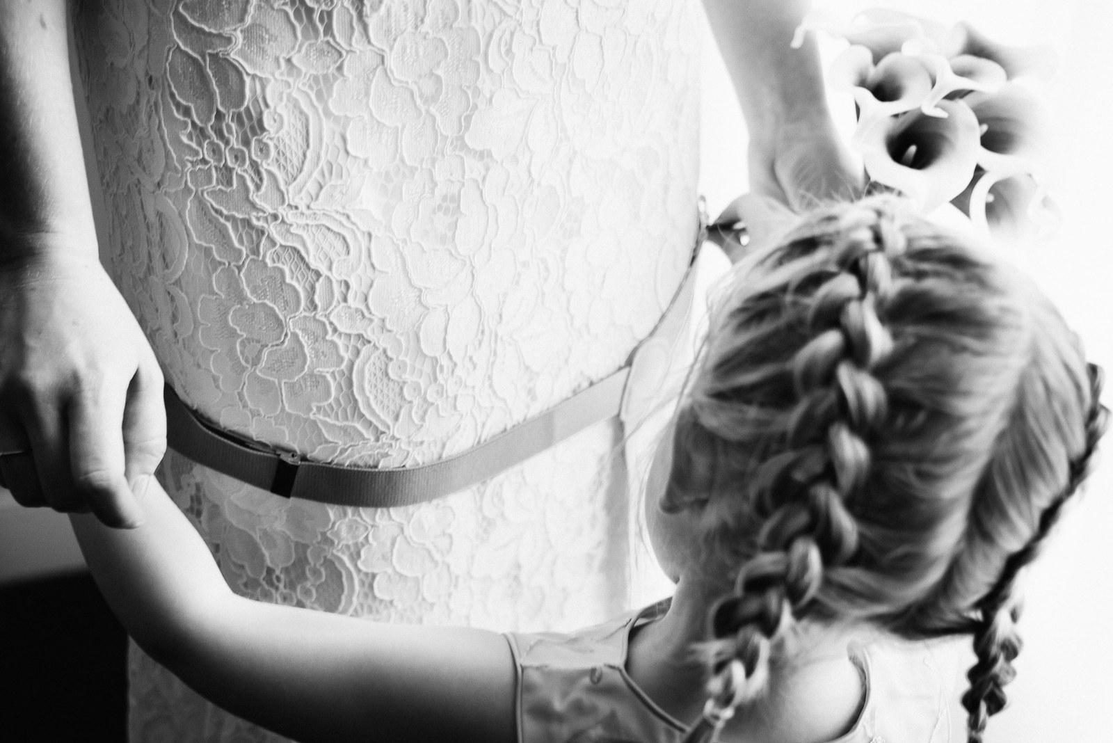 Black and white close-up of the back of the lace gown, a young flower girl alongside