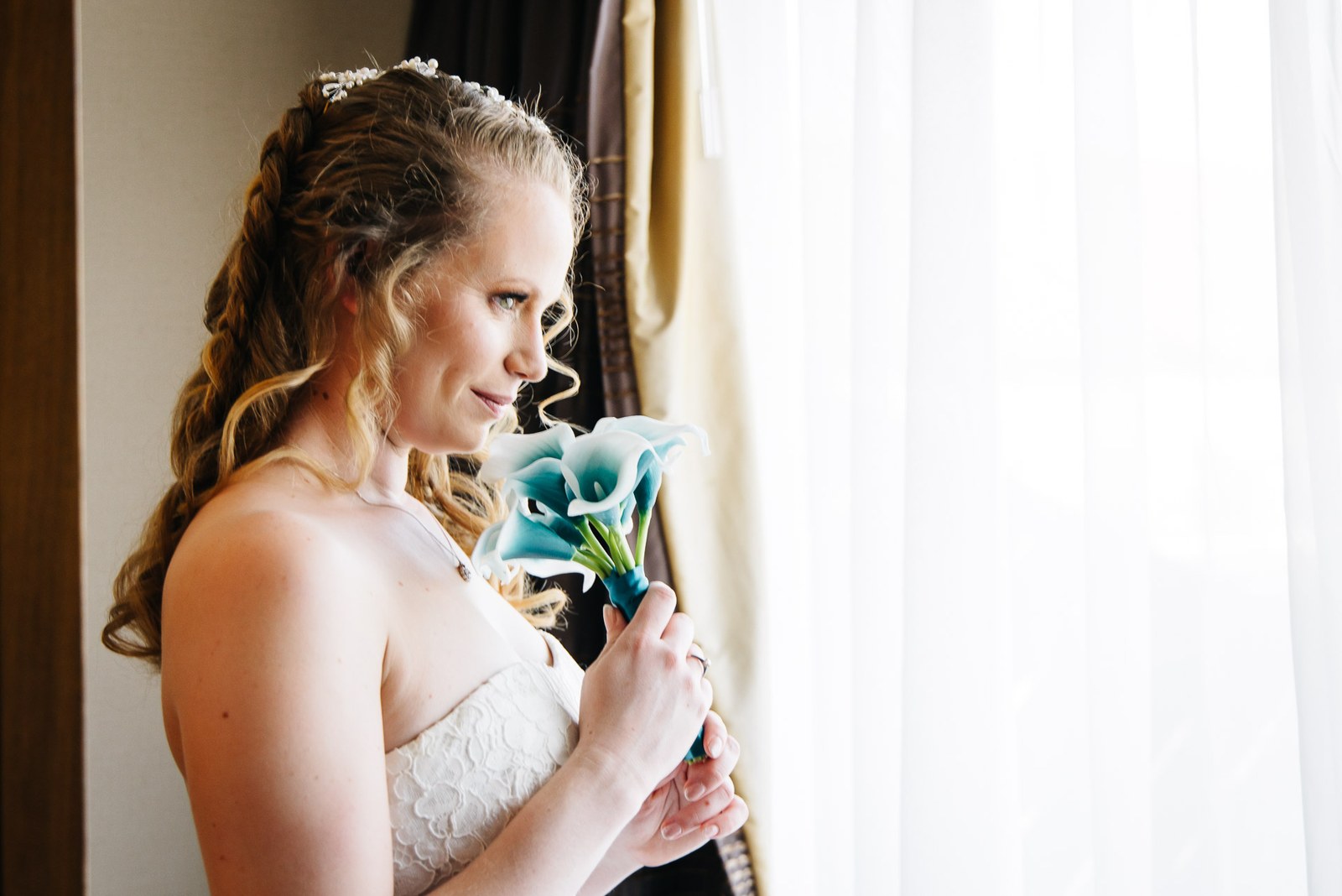The bride holding a calla lily bouquet in soft window light