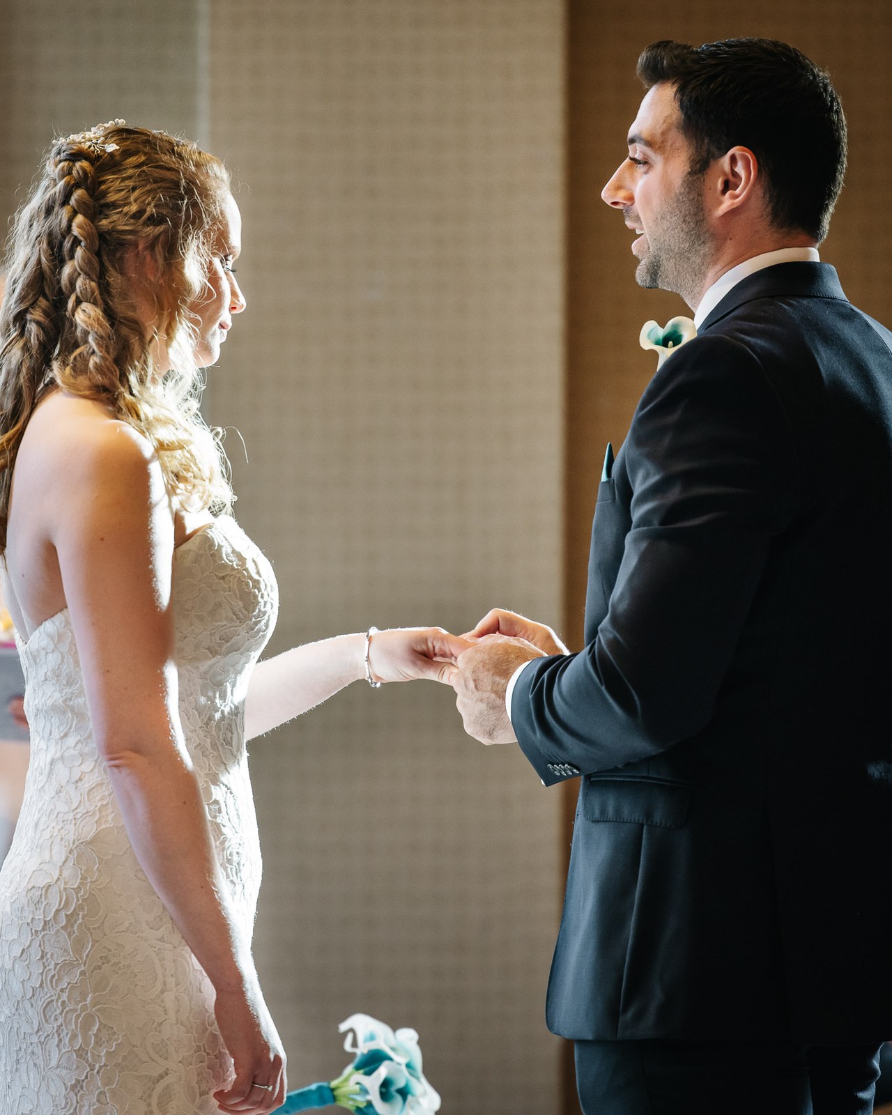 The bride and groom facing each other and holding hands during the ceremony