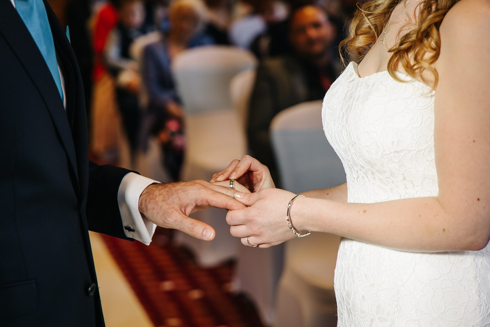 Close-up of the bride sliding the wedding ring onto the groom's finger