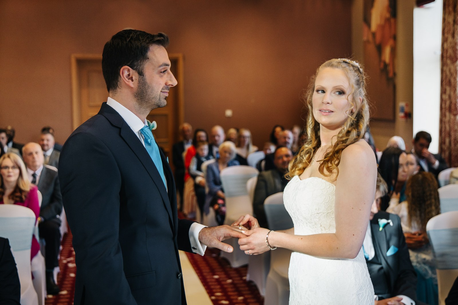The bride and groom exchange vows as guests look on behind them