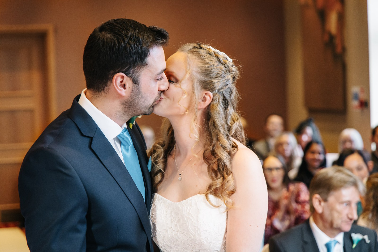 The newlyweds share their first kiss as a married couple, guests behind