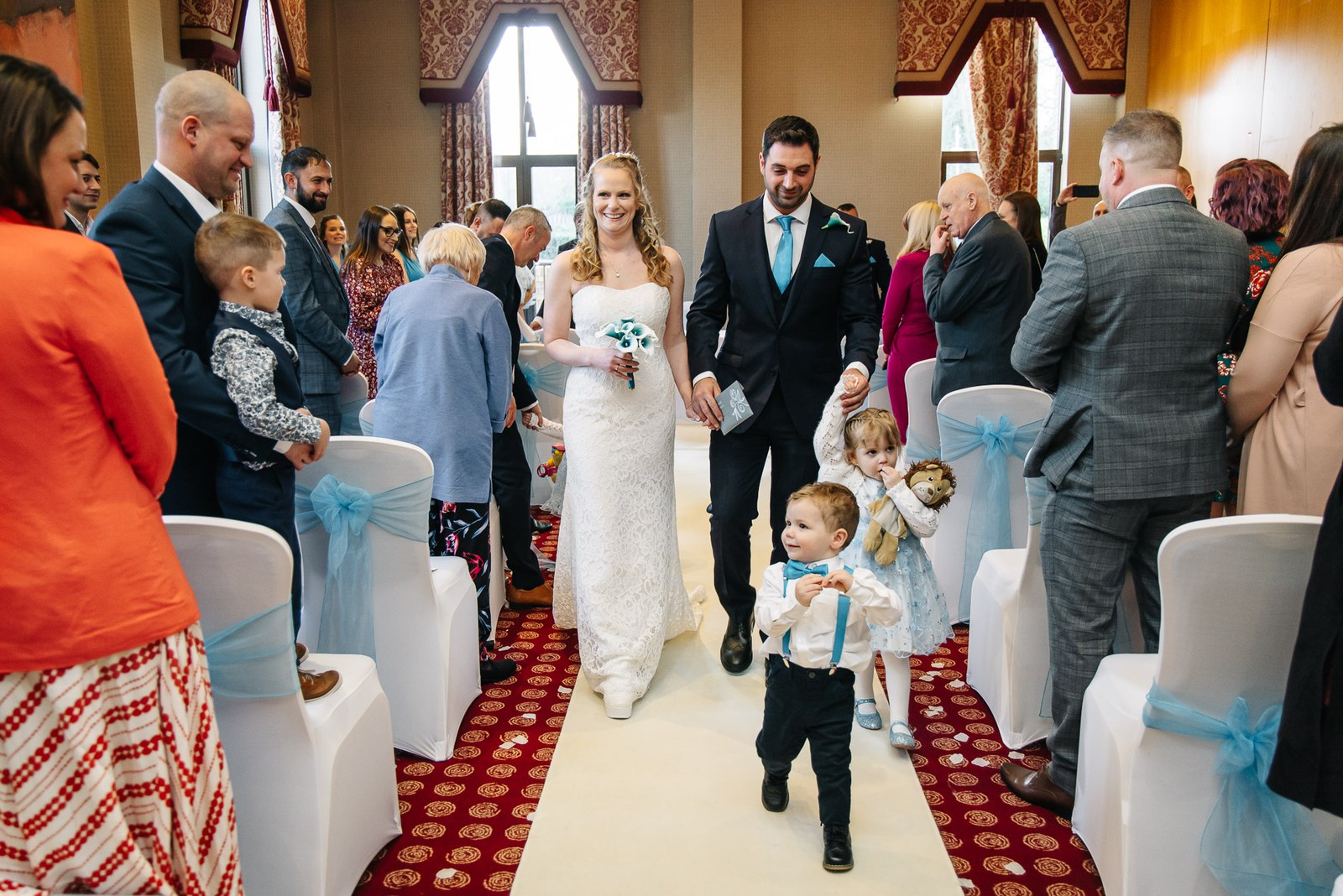 The newlyweds walk back down the aisle together, a young page boy ahead