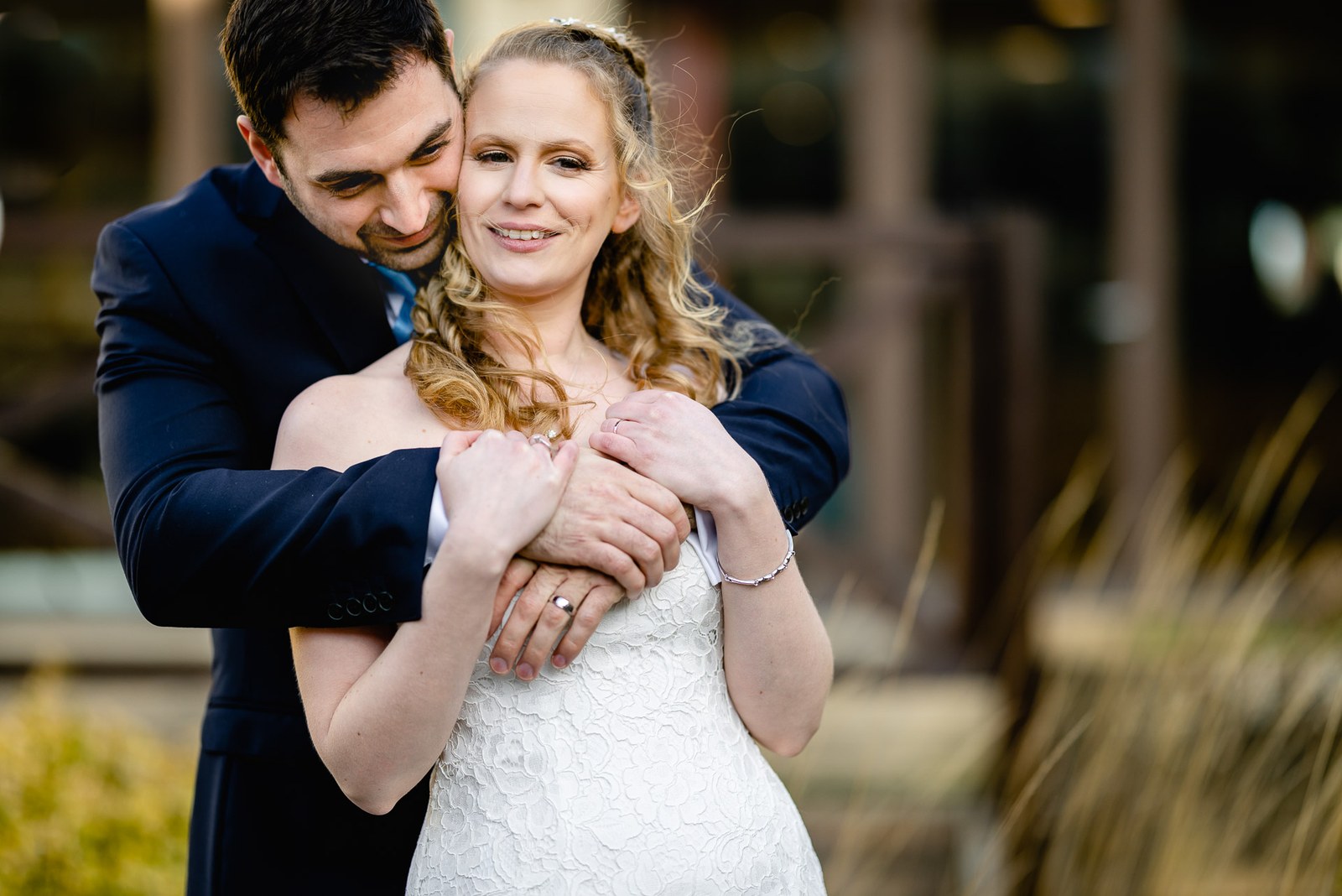 The groom holding the bride from behind in the grasses of the hotel grounds