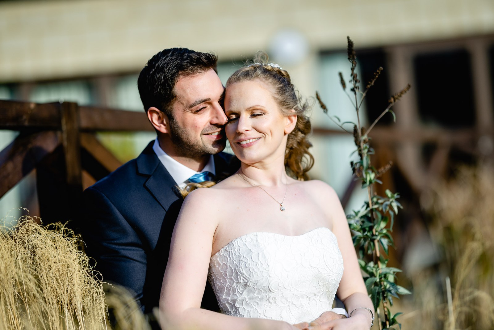 The bride and groom cheek to cheek among swaying ornamental grasses