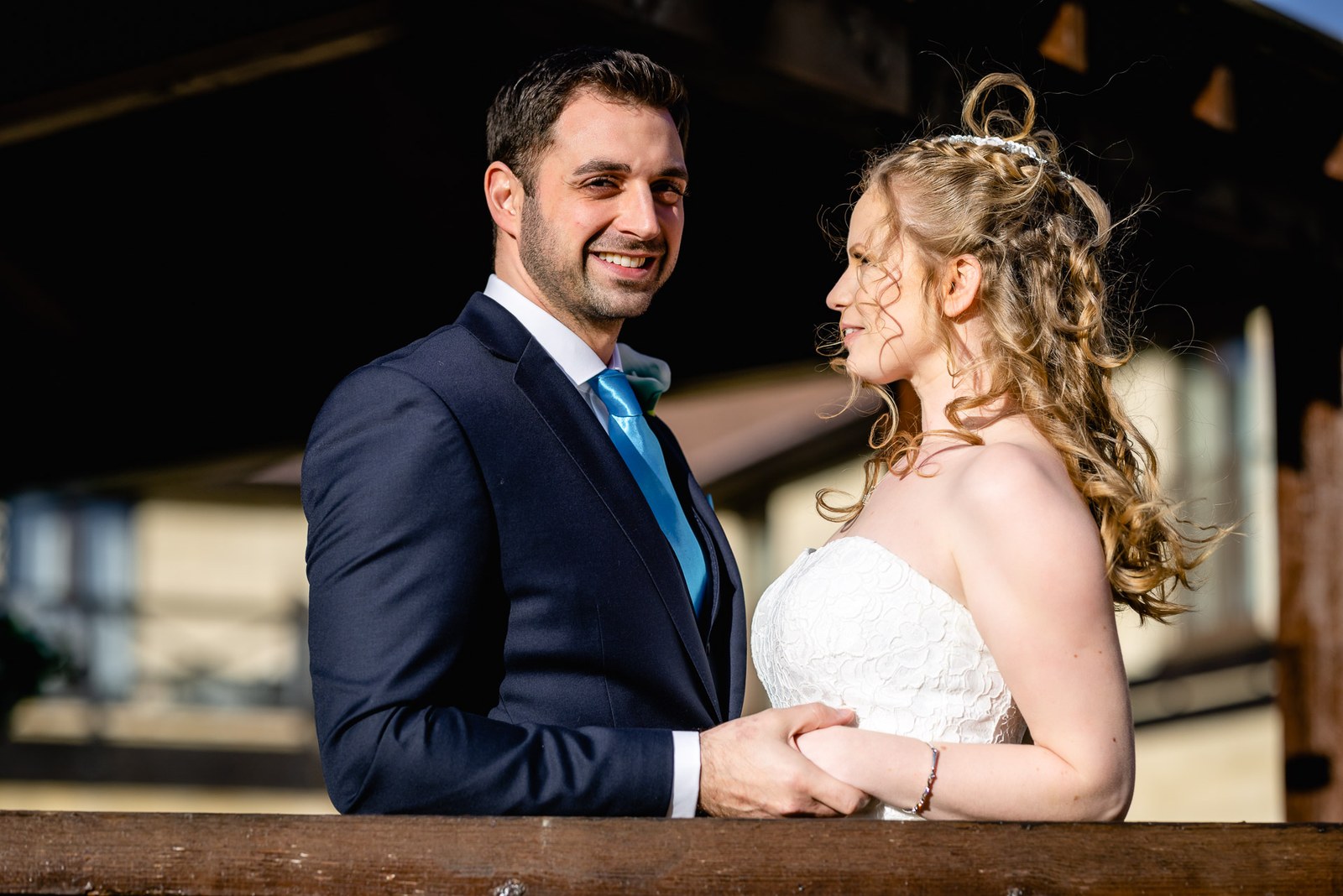The bride and groom face to face in sunshine, The Hampshire Court Hotel behind
