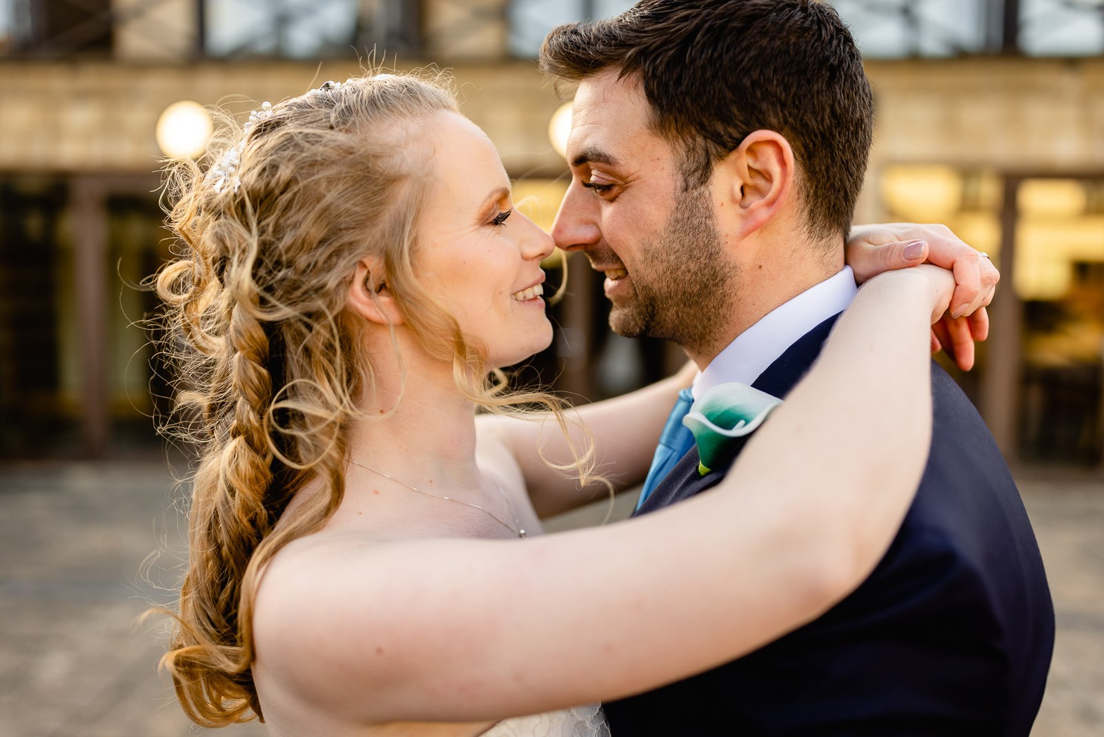 The bride and groom close together, nose to nose, in the hotel courtyard