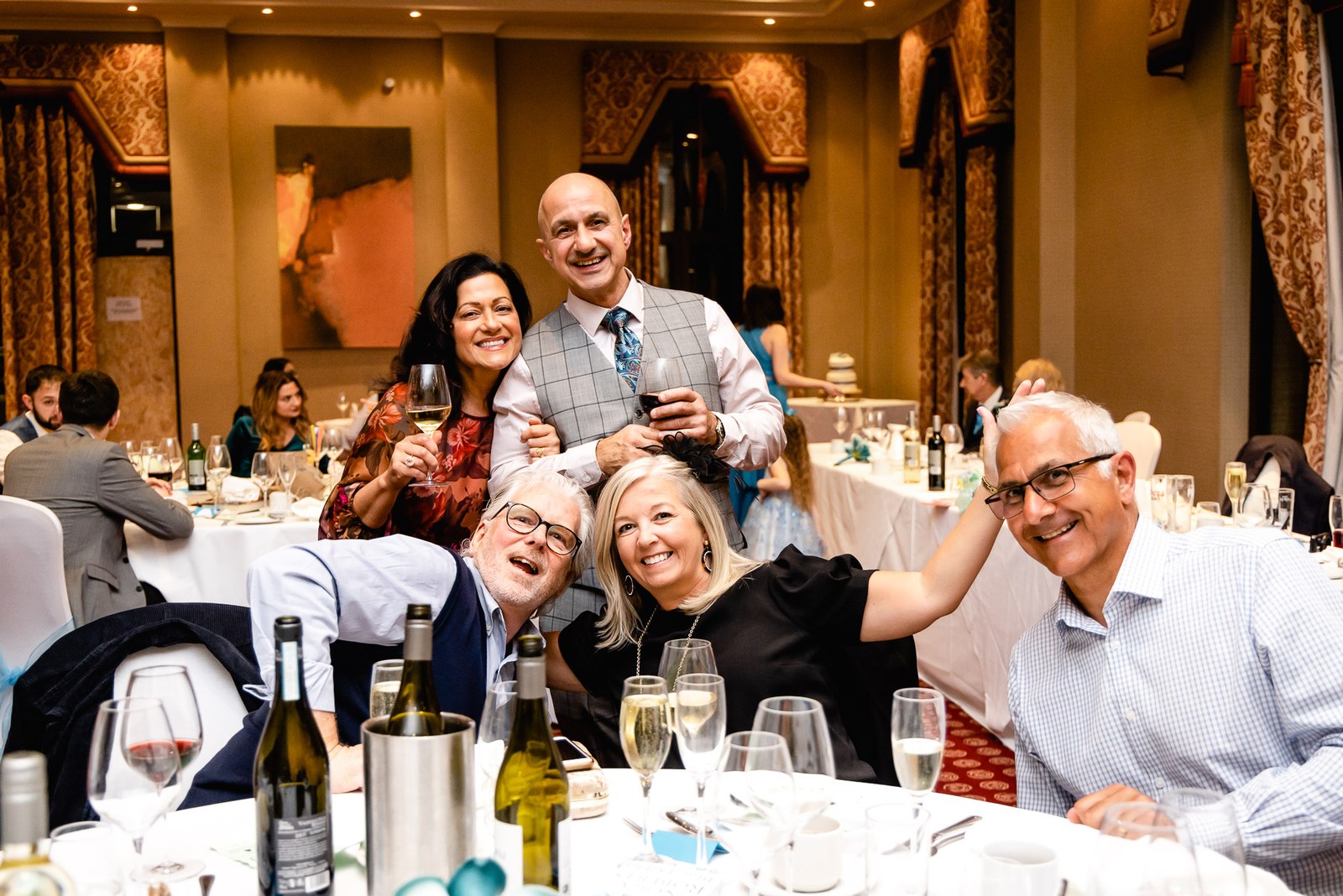 Guests laughing together around a reception table set with wine and glasses