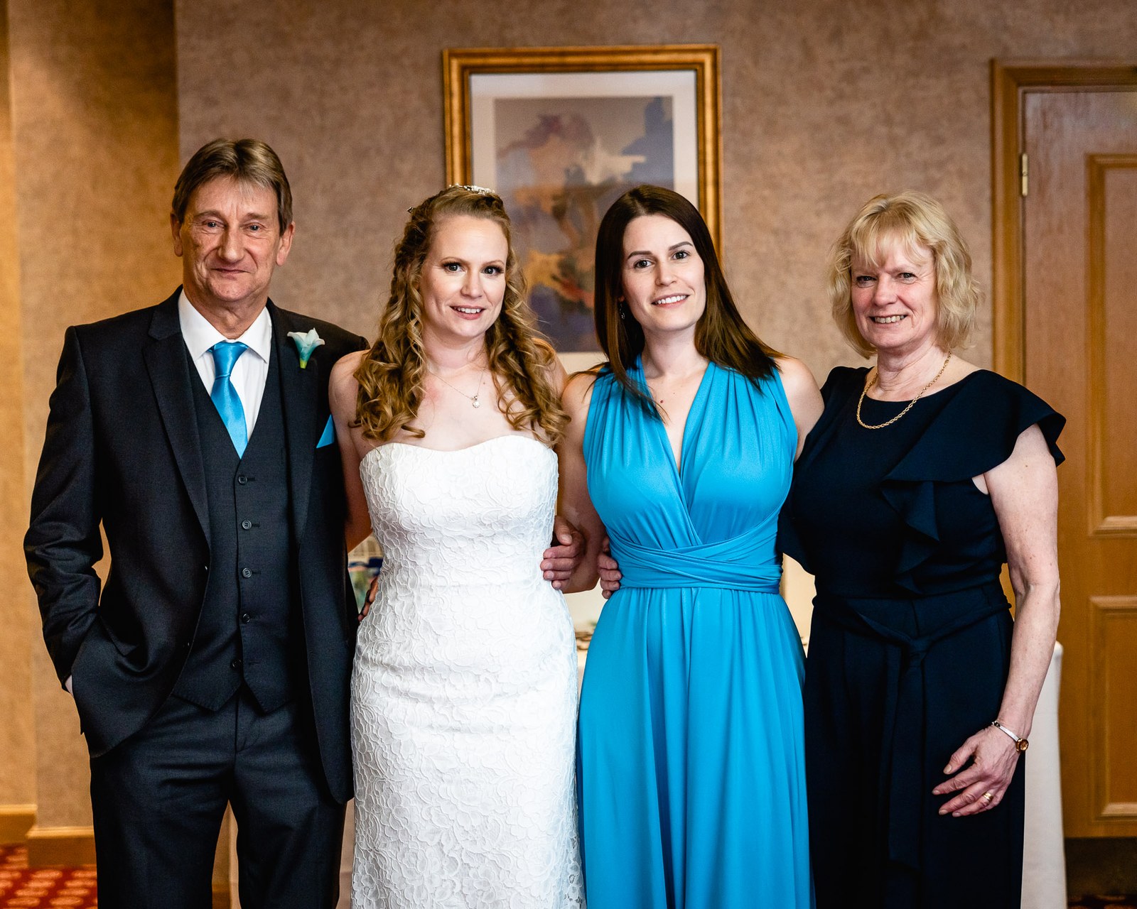 Family group portrait of the bride with her father, a bridesmaid and her mother
