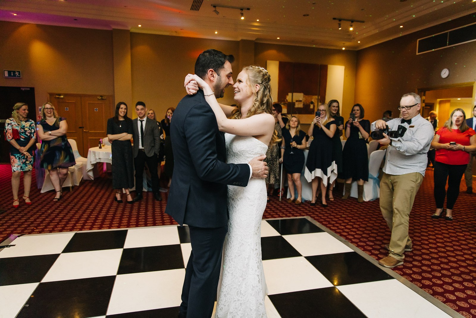 The couple's first dance on a black-and-white chequered floor as guests watch