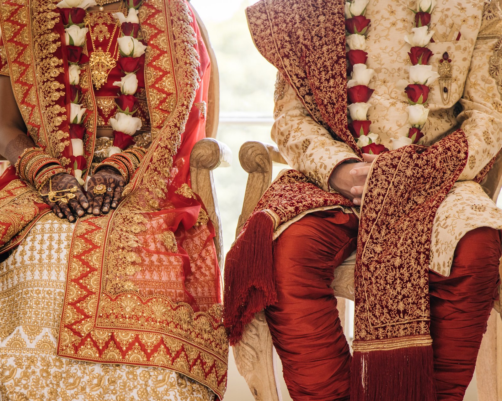 Close-up of the seated couple's laps and floral garlands during the rituals