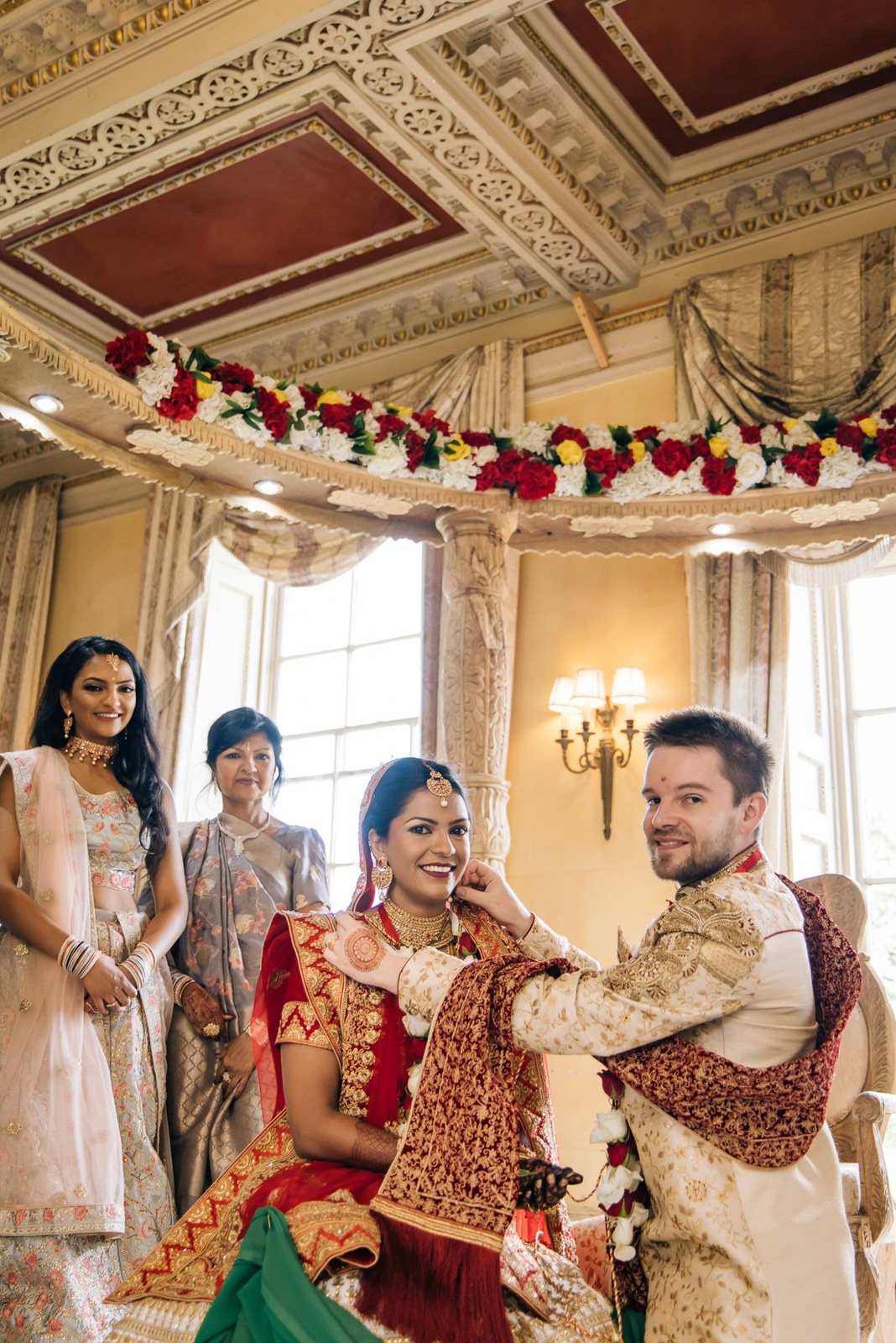 Bride and groom smiling under the mandap as family gather around