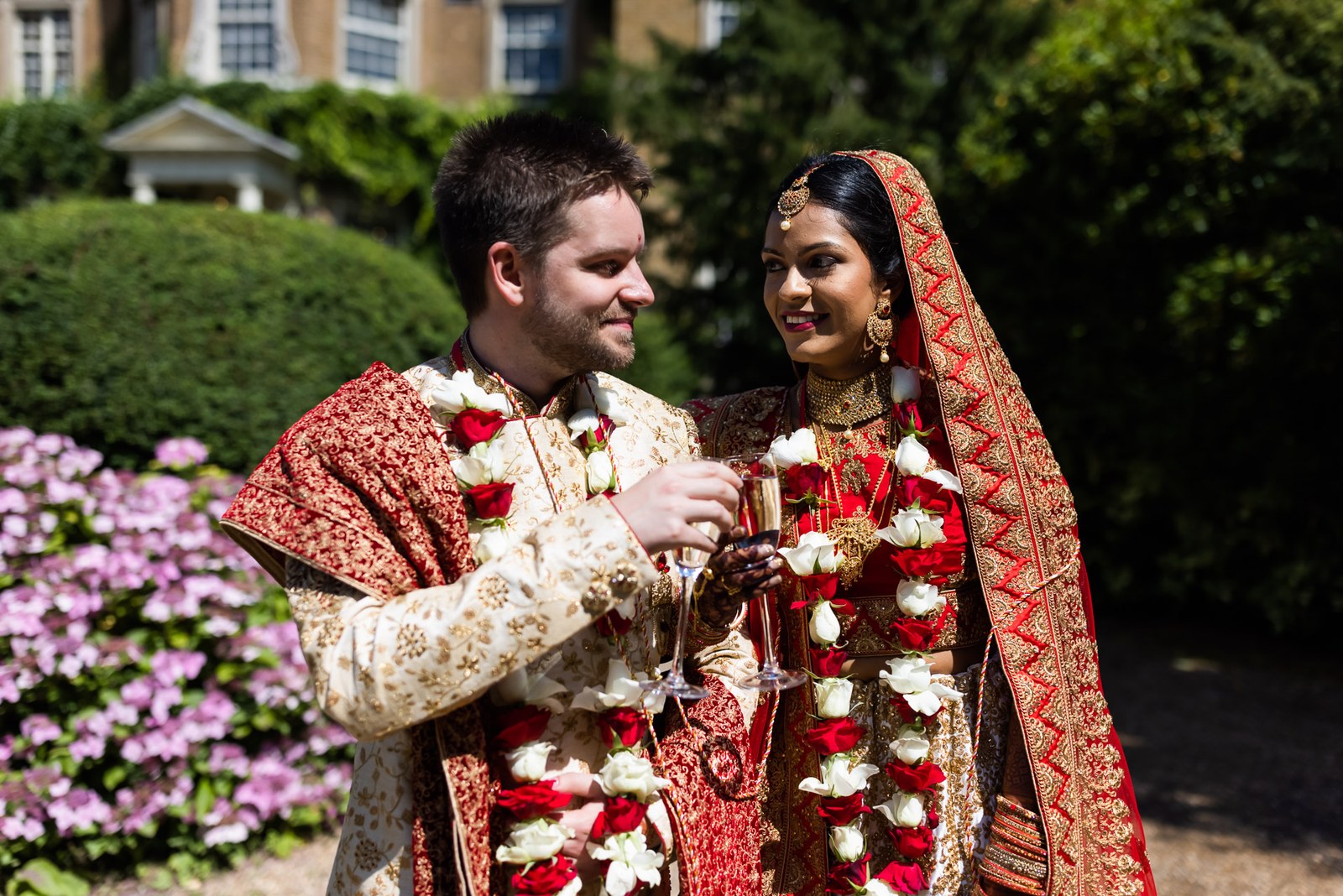 The couple sharing a toast in the garden beside pink hydrangeas