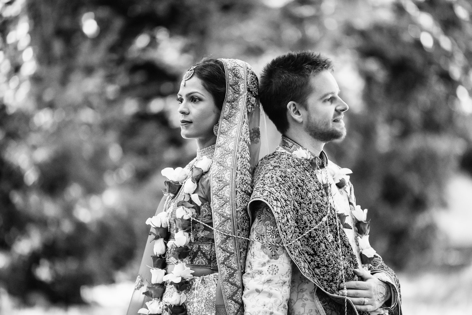Black-and-white portrait of the couple back to back among the greenery